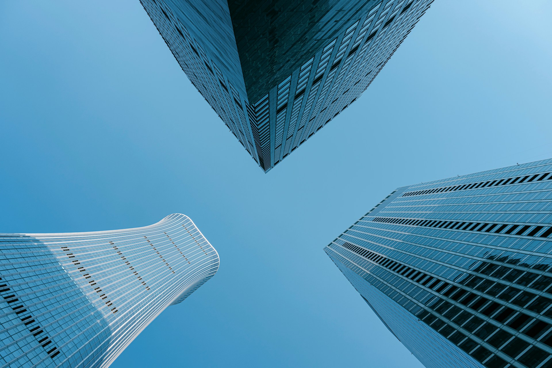 Three skyscrapers point upward against the blue sky.