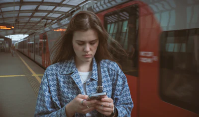 A traveller reading her phone on a station platform