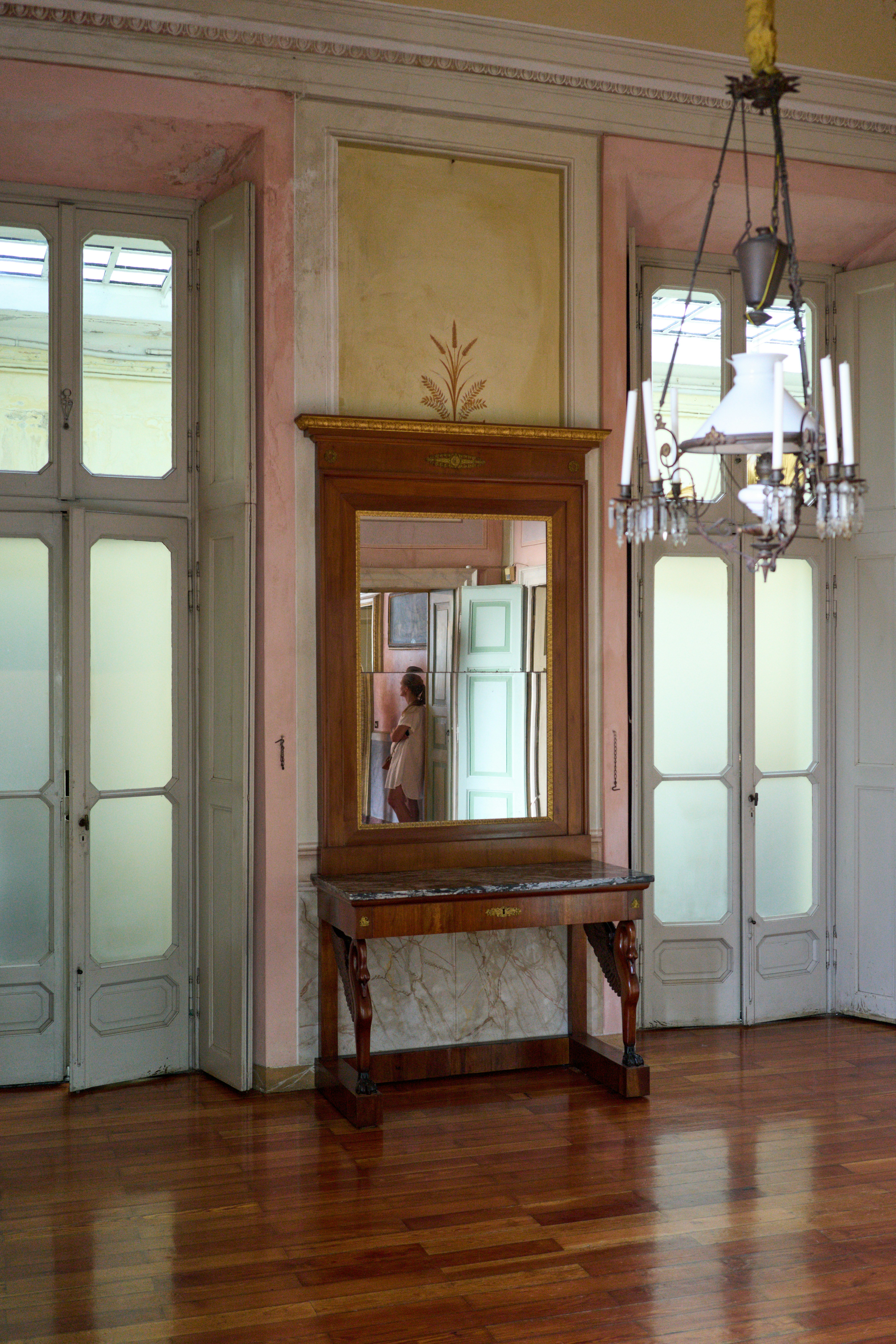 An ornate room with a mirror and chandelier.