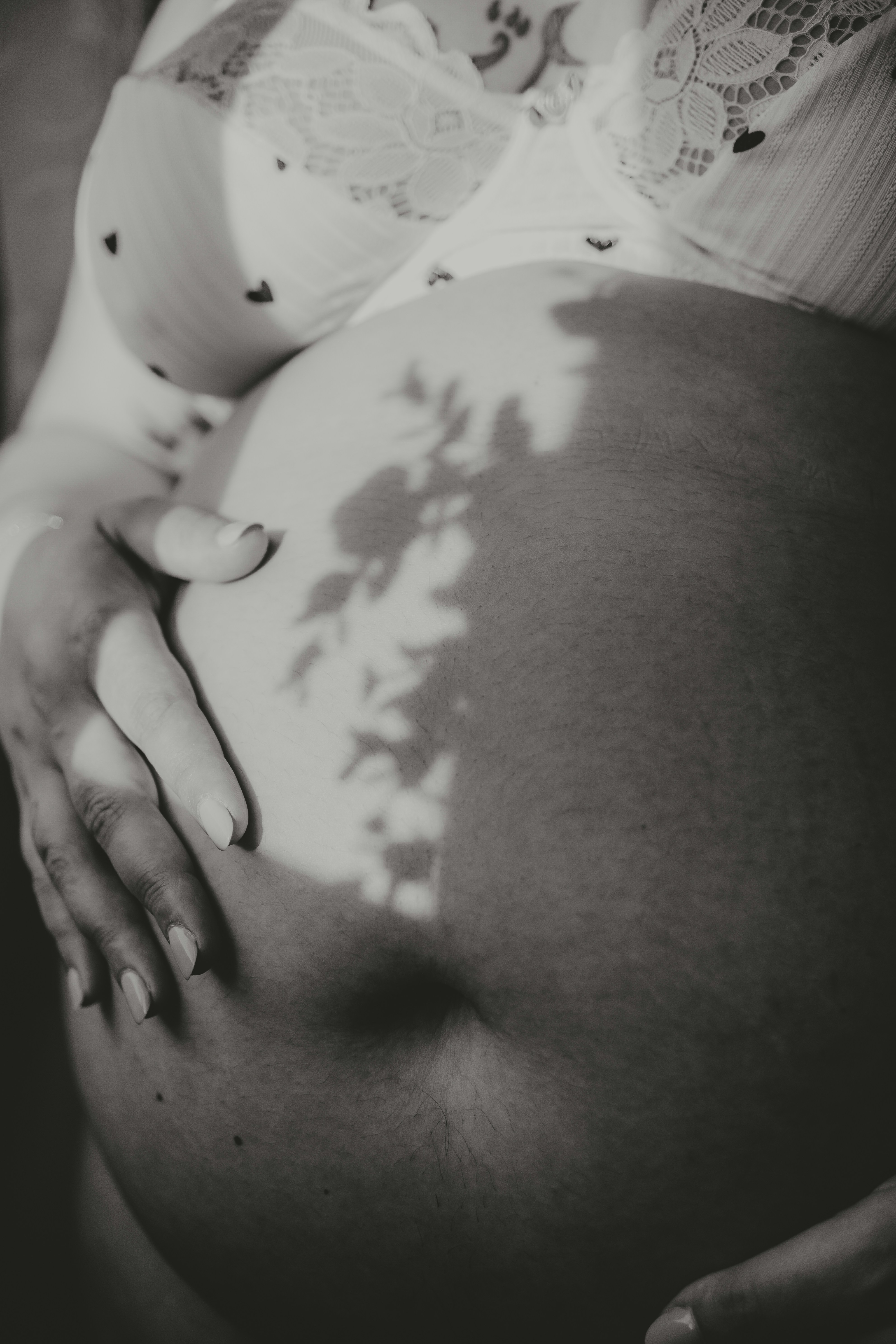 Pregnant belly being held in shadow.