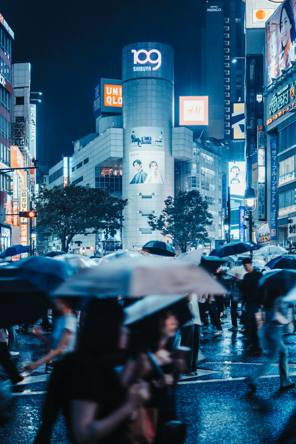 A crowd crosses the neon-lit Shibuya intersection in Tokyo after dark