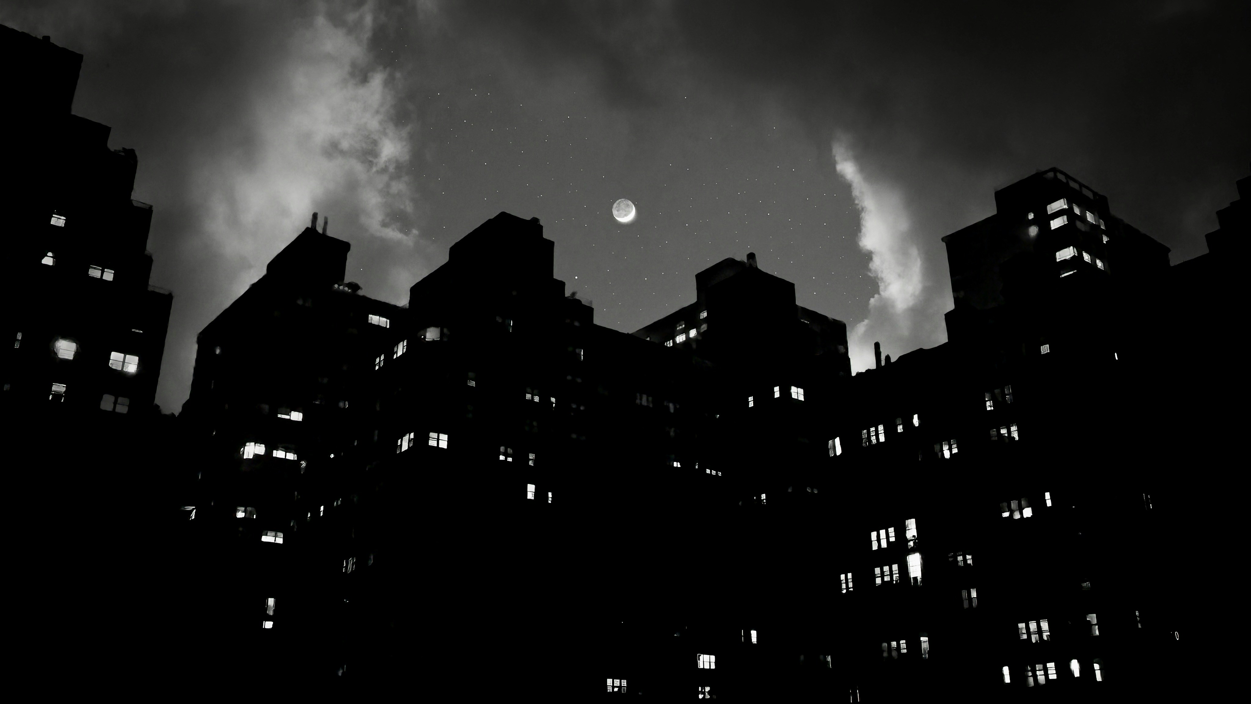 Buildings silhouetted against a cloudy, moonlit sky.