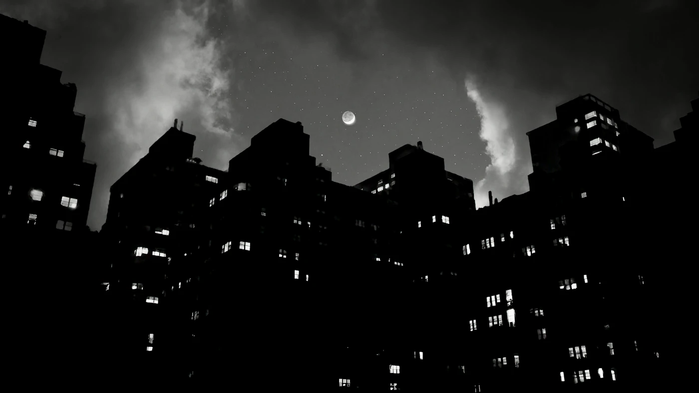 Apartment towers silhouetted against a cloudy, moonlit sky
