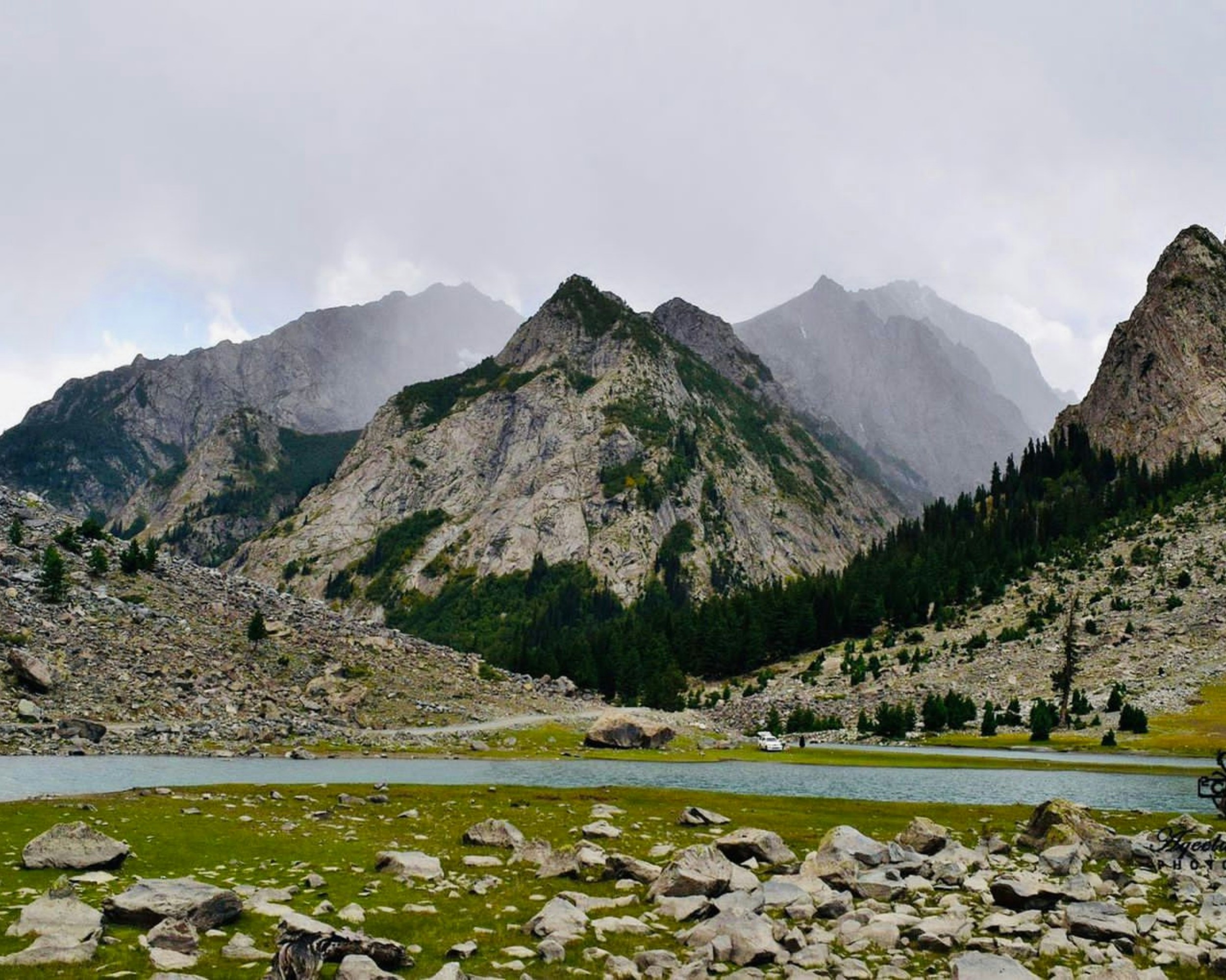 Montañas y un lago sereno bajo un cielo nublado.