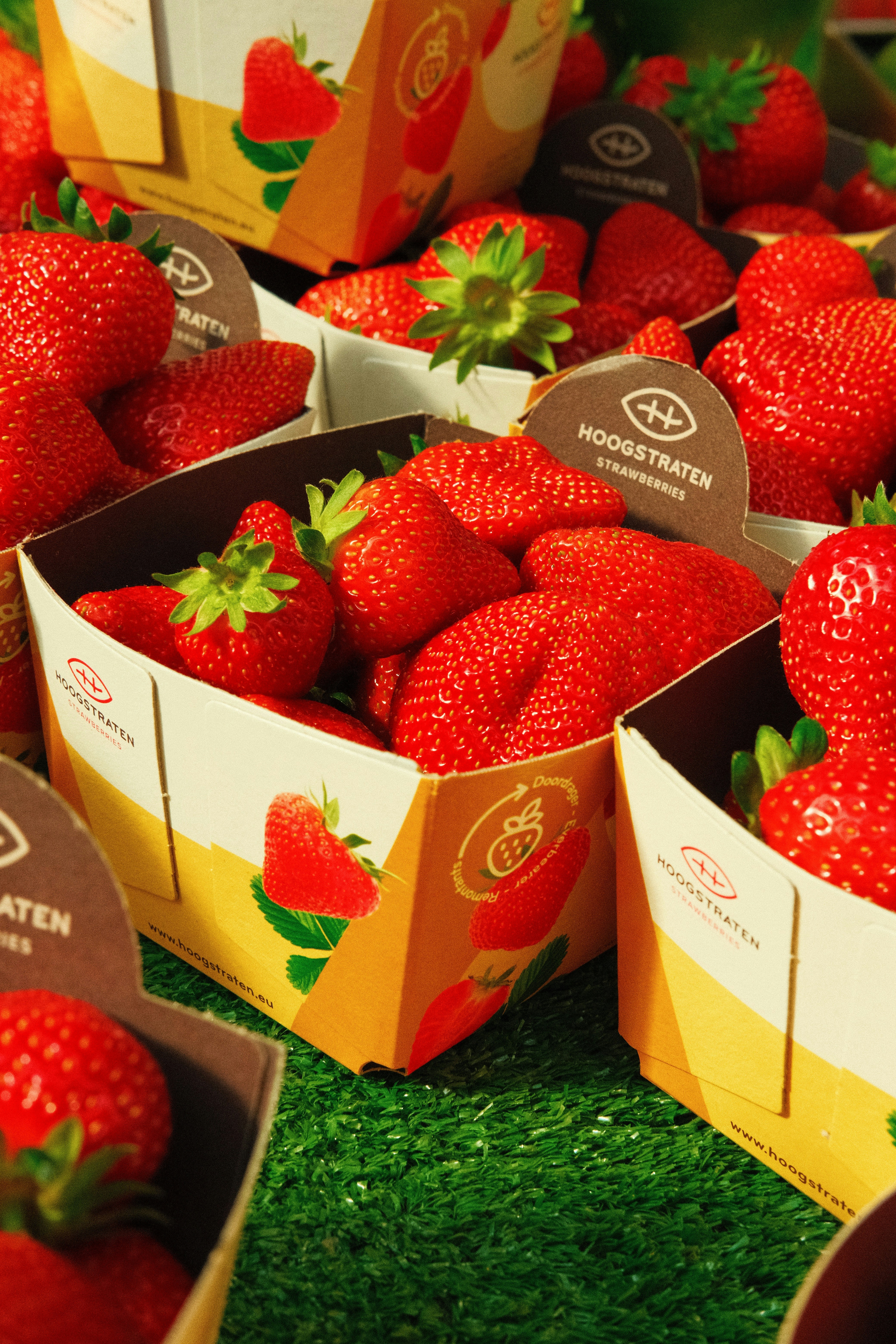 Fresh, ripe strawberries are displayed in containers.