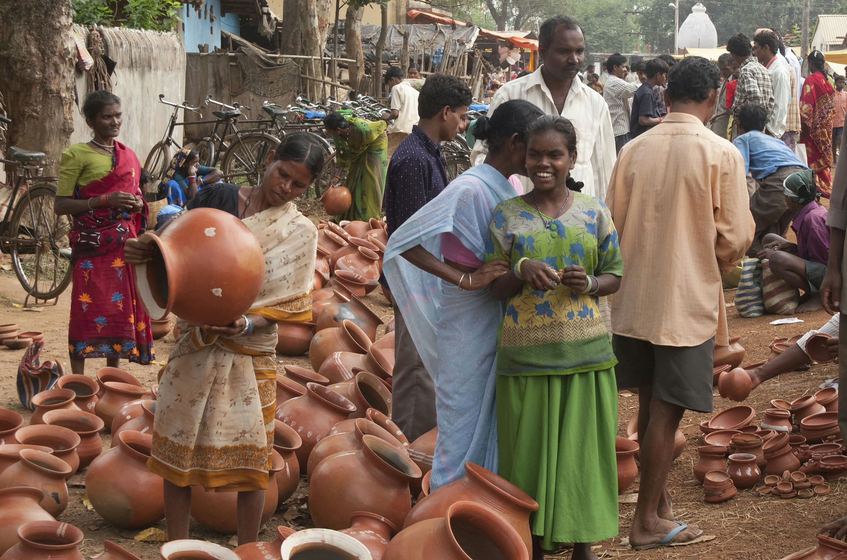 People browse pottery at a bustling outdoor market.
