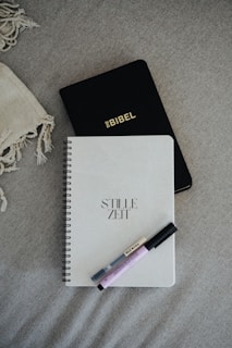 Bible, journal, and pens lie on a soft surface.