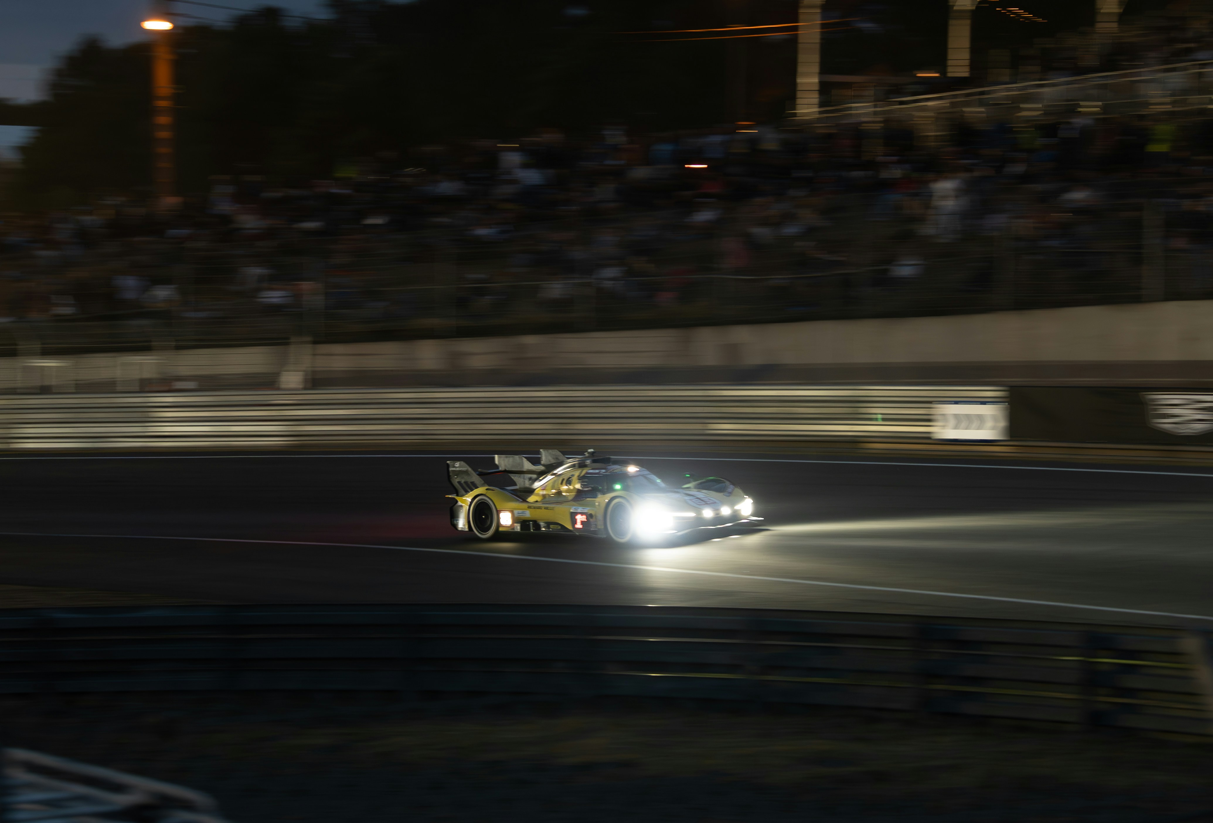 Night racing action at Le Mans with multiple hypercars battling for position under floodlights - sports car news