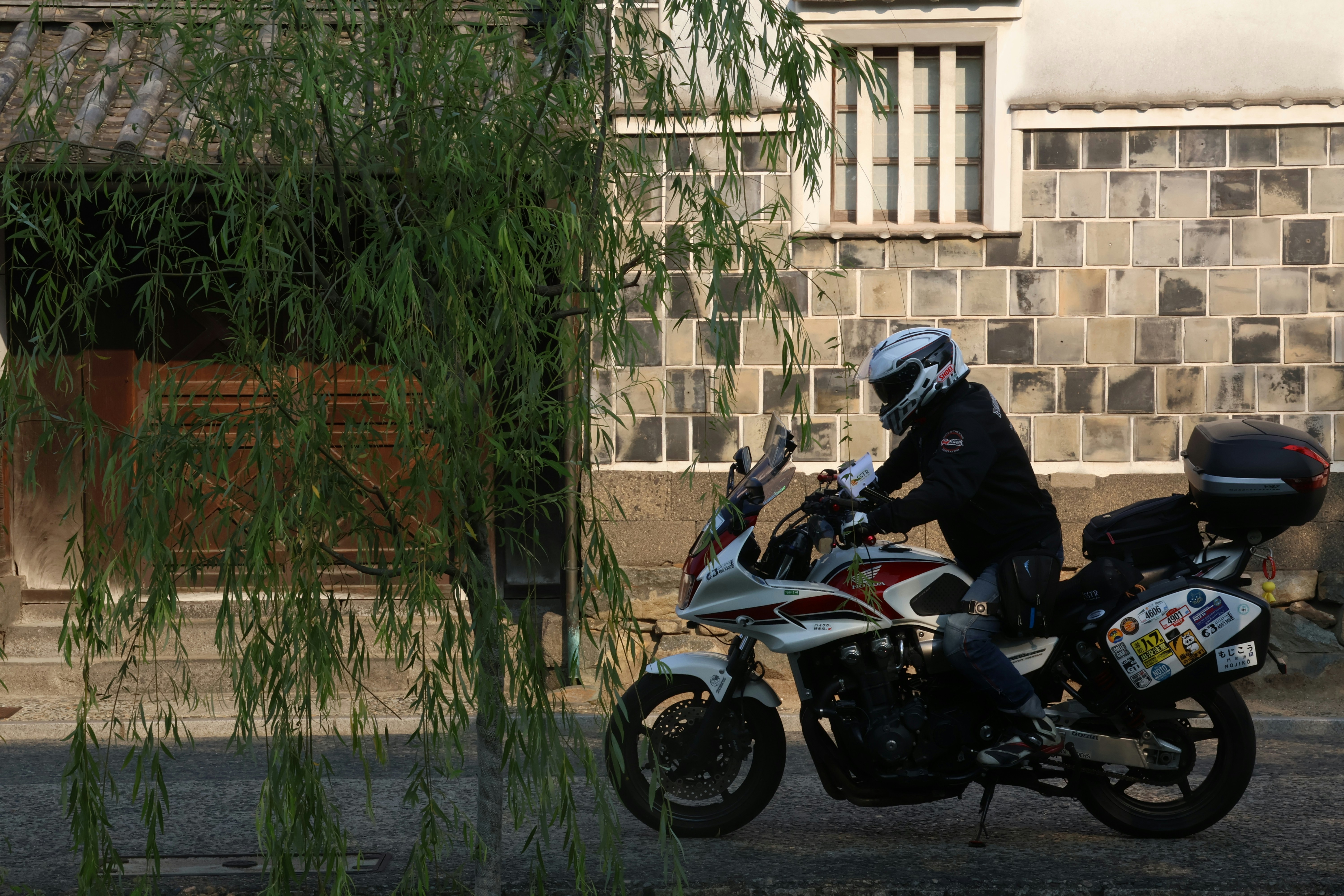 A person rides a motorcycle near a building.