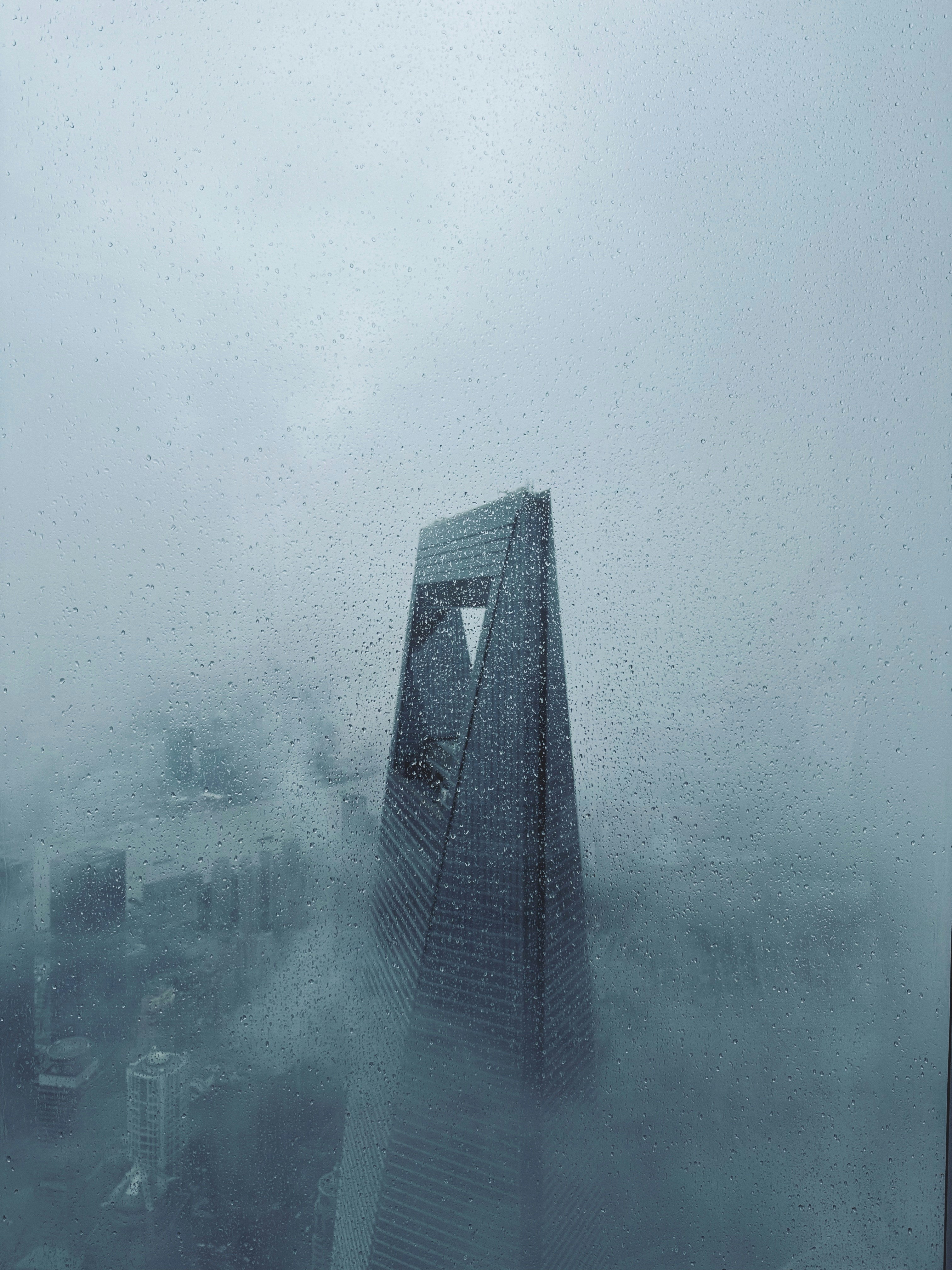 Un grattacielo squarcia la nebbia in una città.