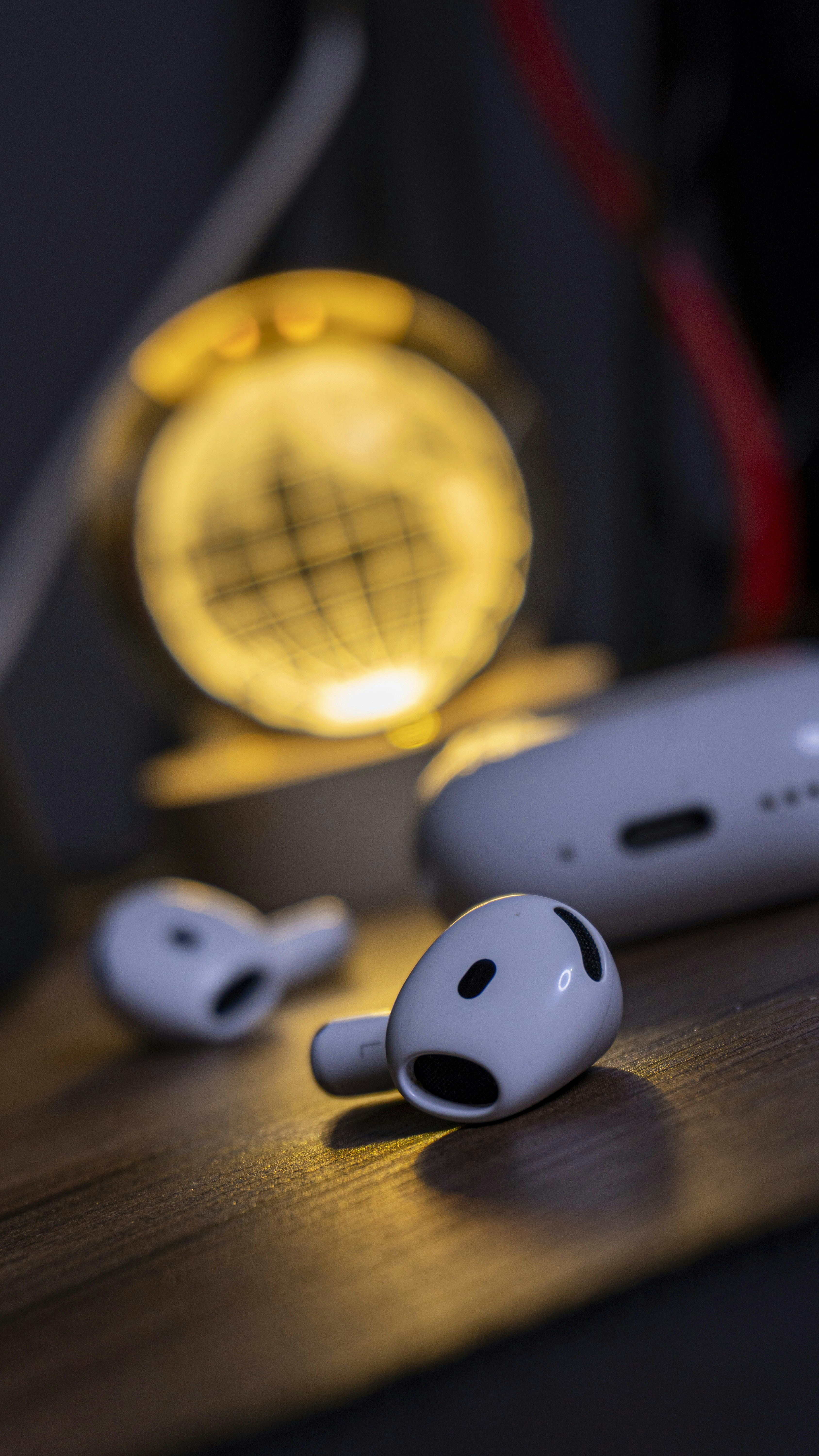 Airpods and their charging case with a glowing orb.