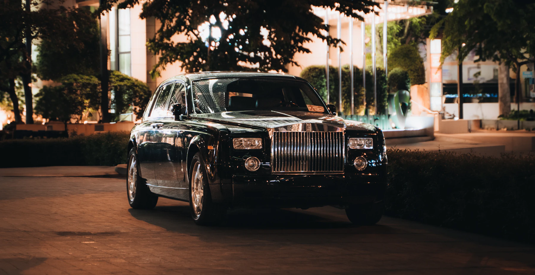 A dark luxury limousine parked at night under city lights