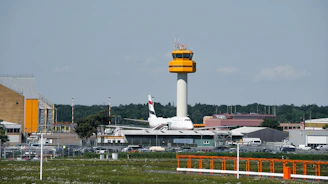 An airplane sits near an airport control tower.