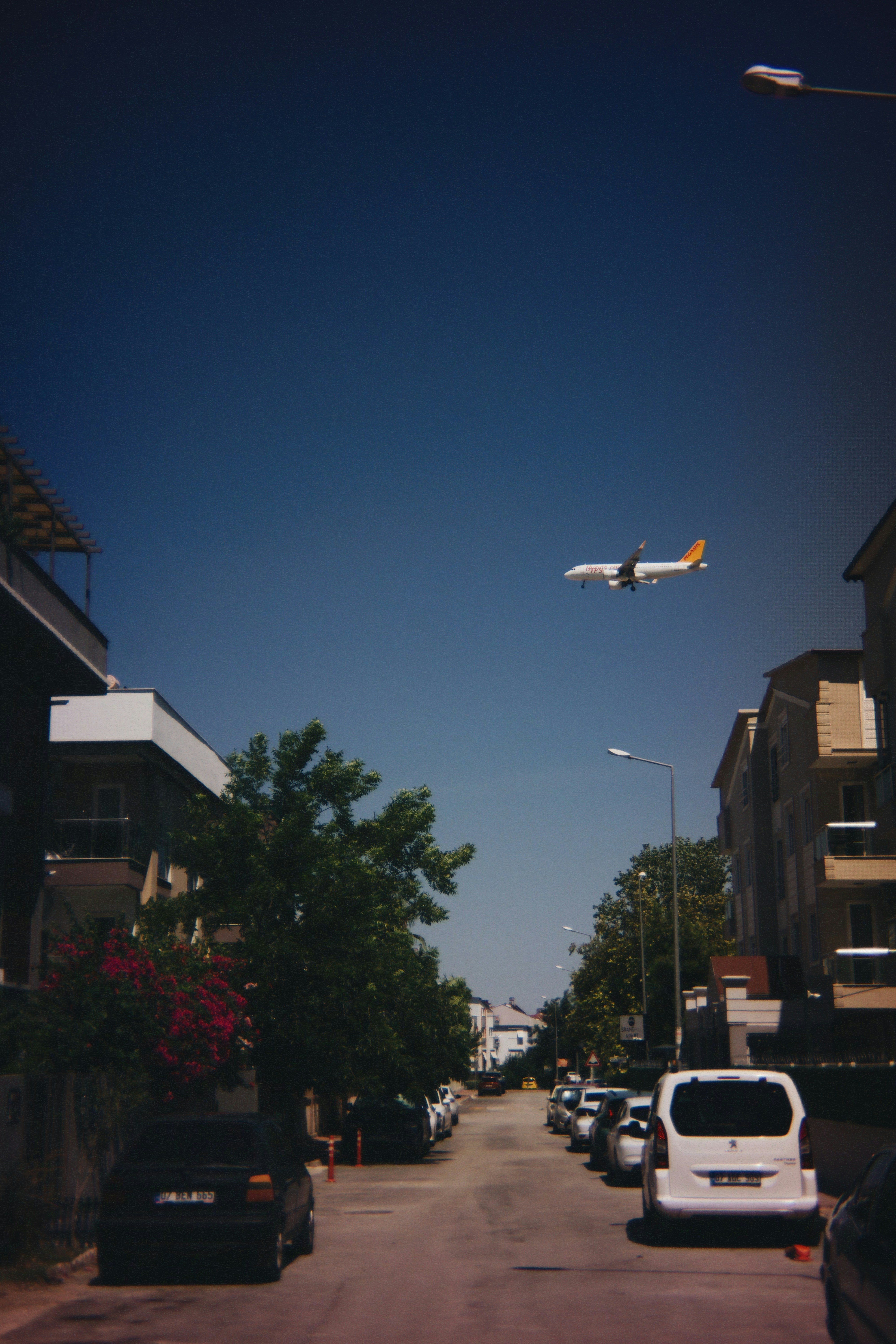 A plane flies low over a city street.