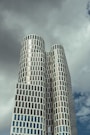 A modern skyscraper towers against a cloudy sky.