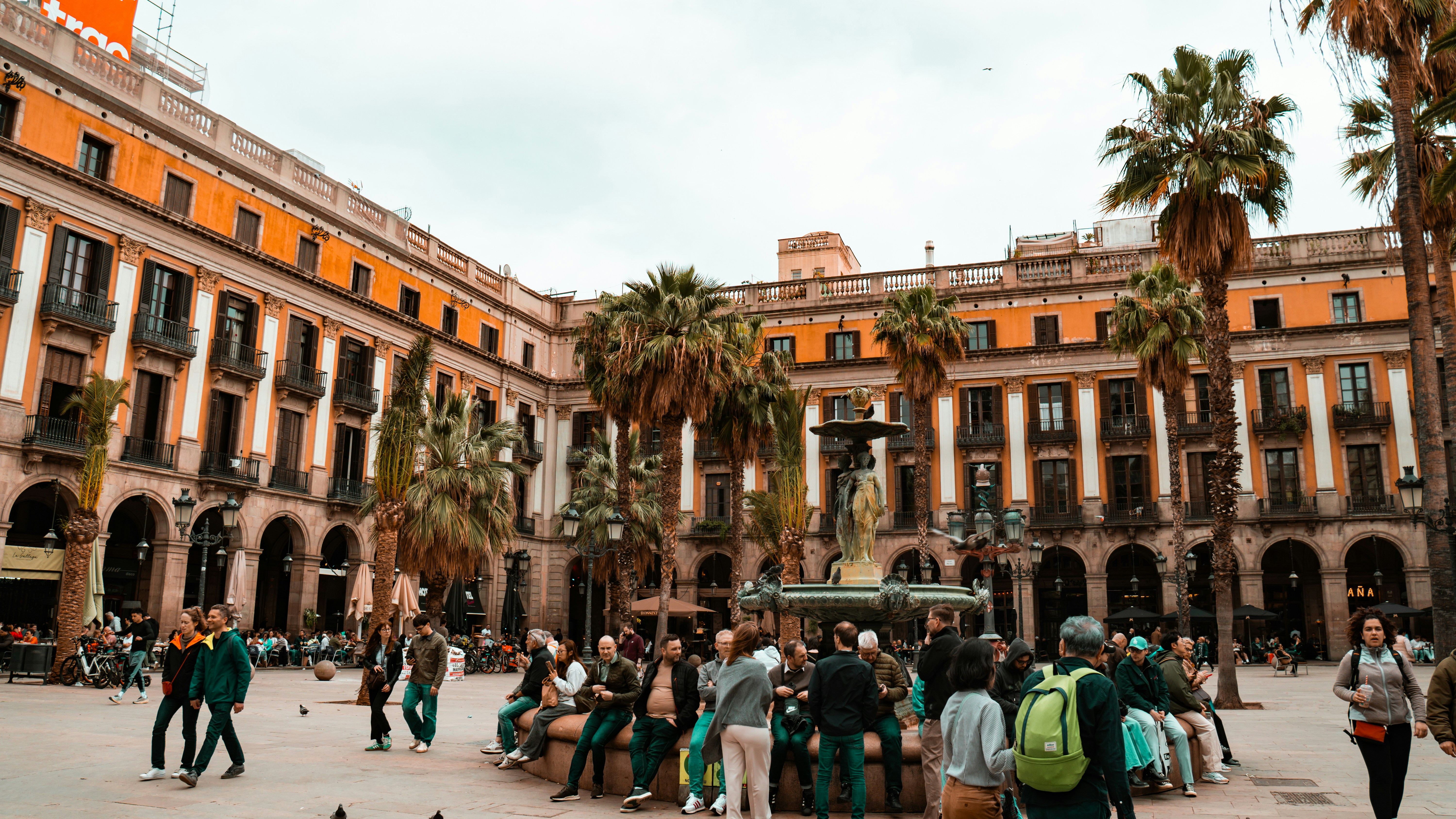A busy plaza with buildings and palm trees.