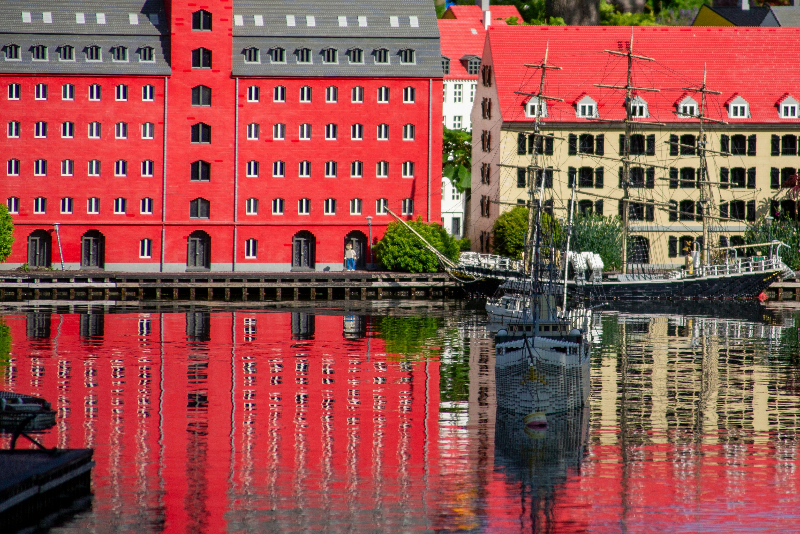Red buildings and a boat reflect in the water.