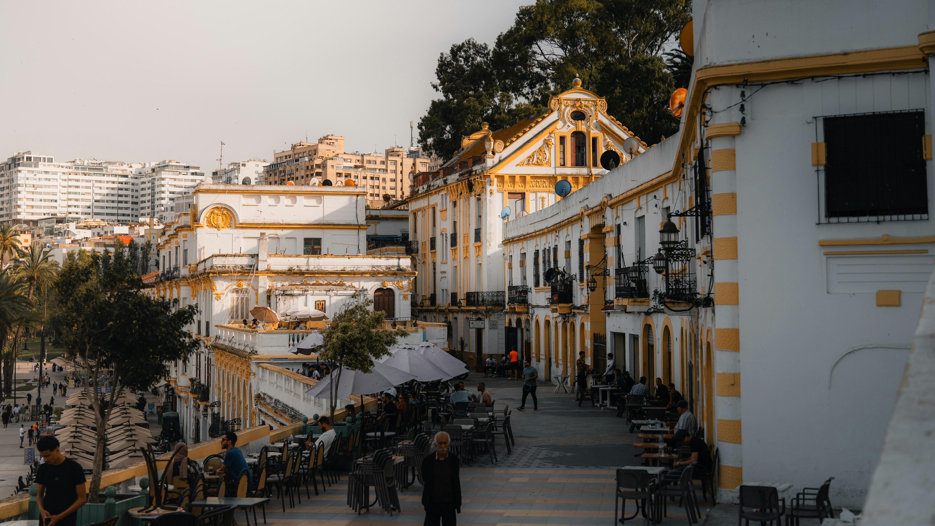 White buildings line a european street with people.