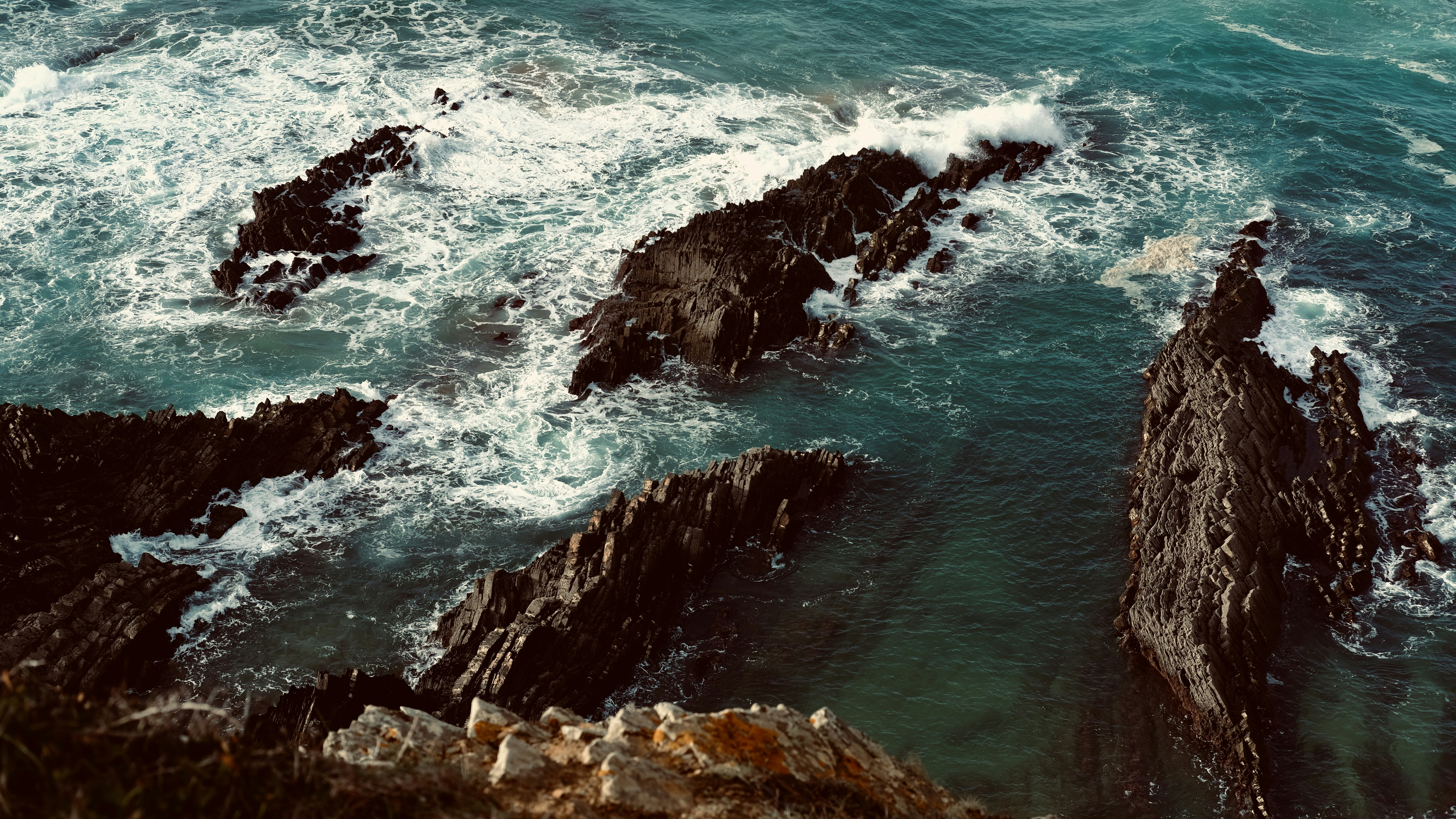 Waves crash against rocky cliffs and the sea.