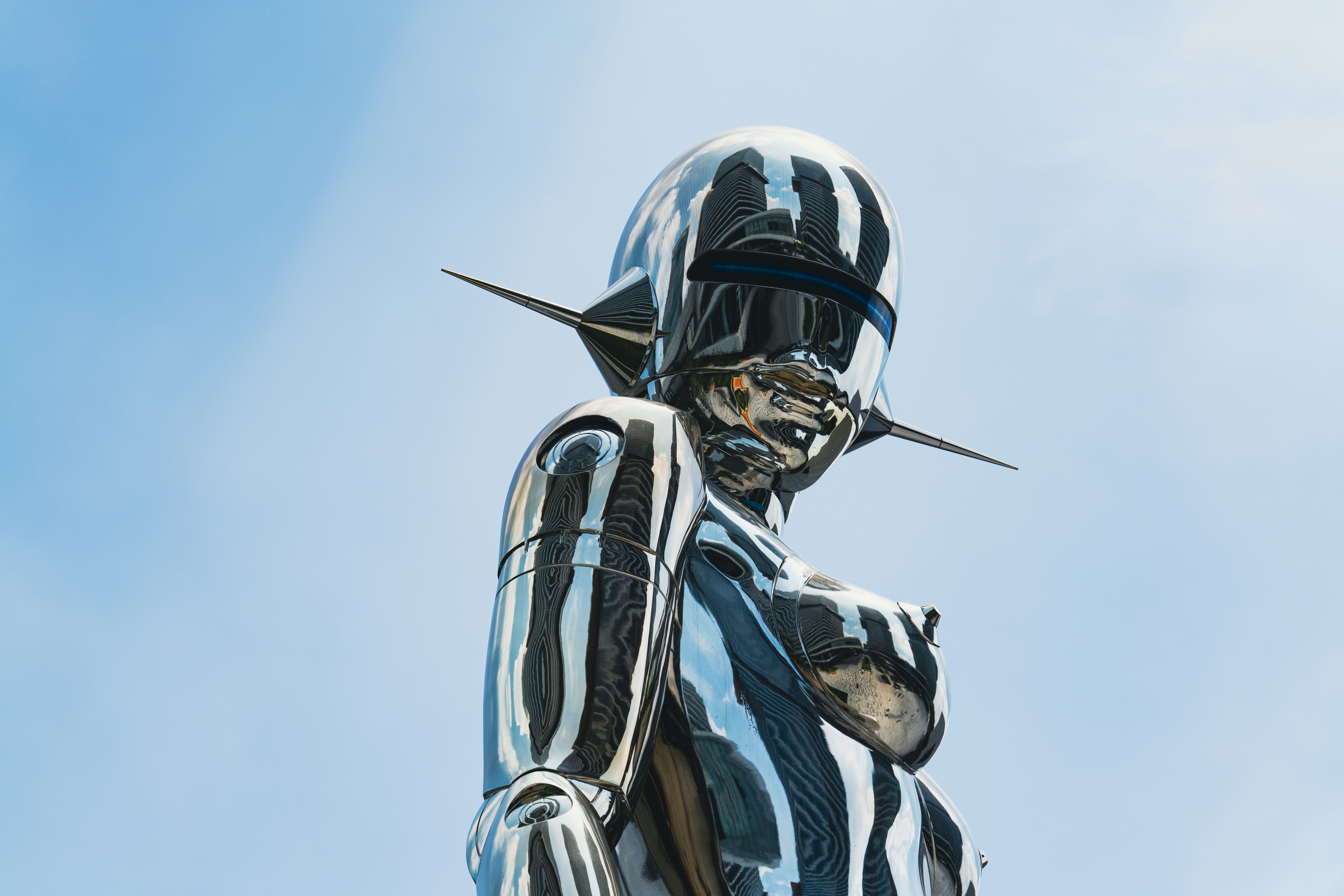 A shiny sculpture stands against a clear sky.