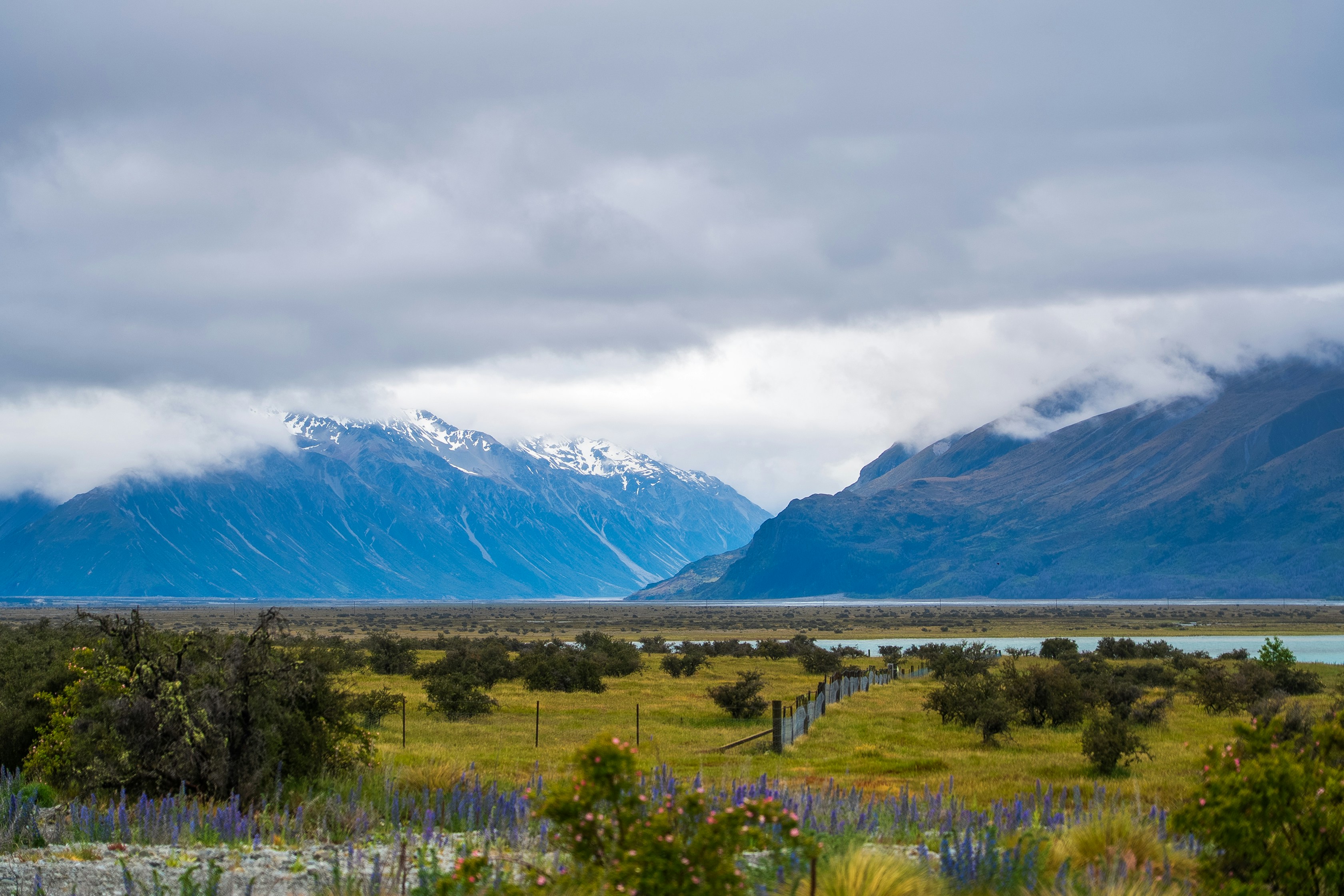 Berge und Felder unter bewölktem Himmel.