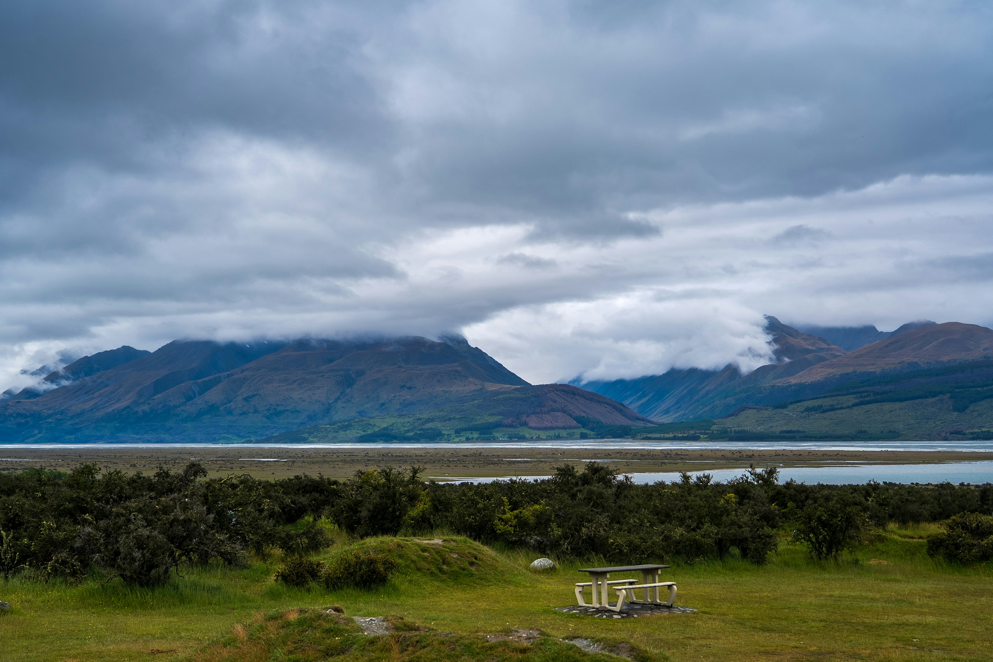 Berge und Wasser unter einem wolkenverhangenen Himmel.