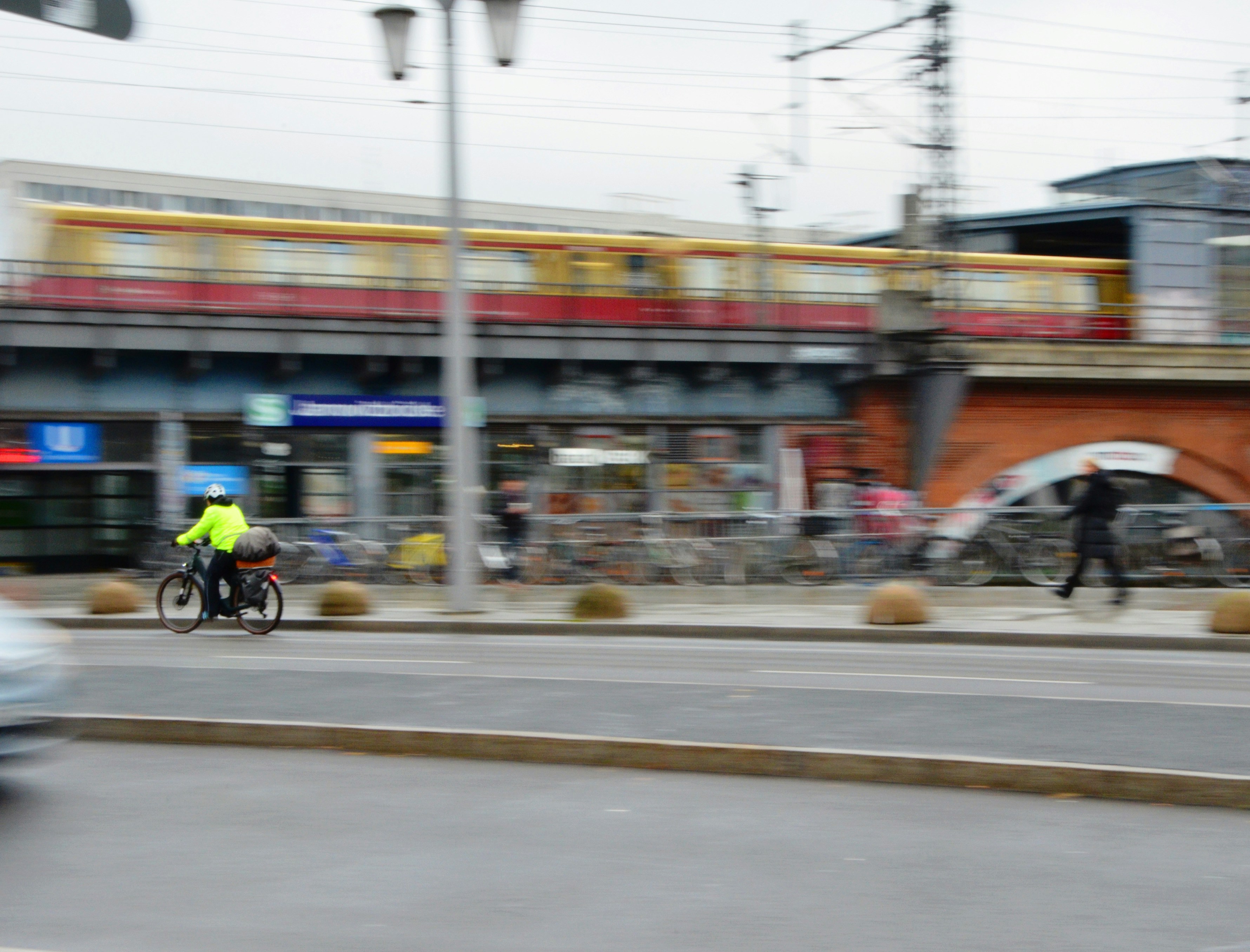 Train passes over a street with cyclists.
