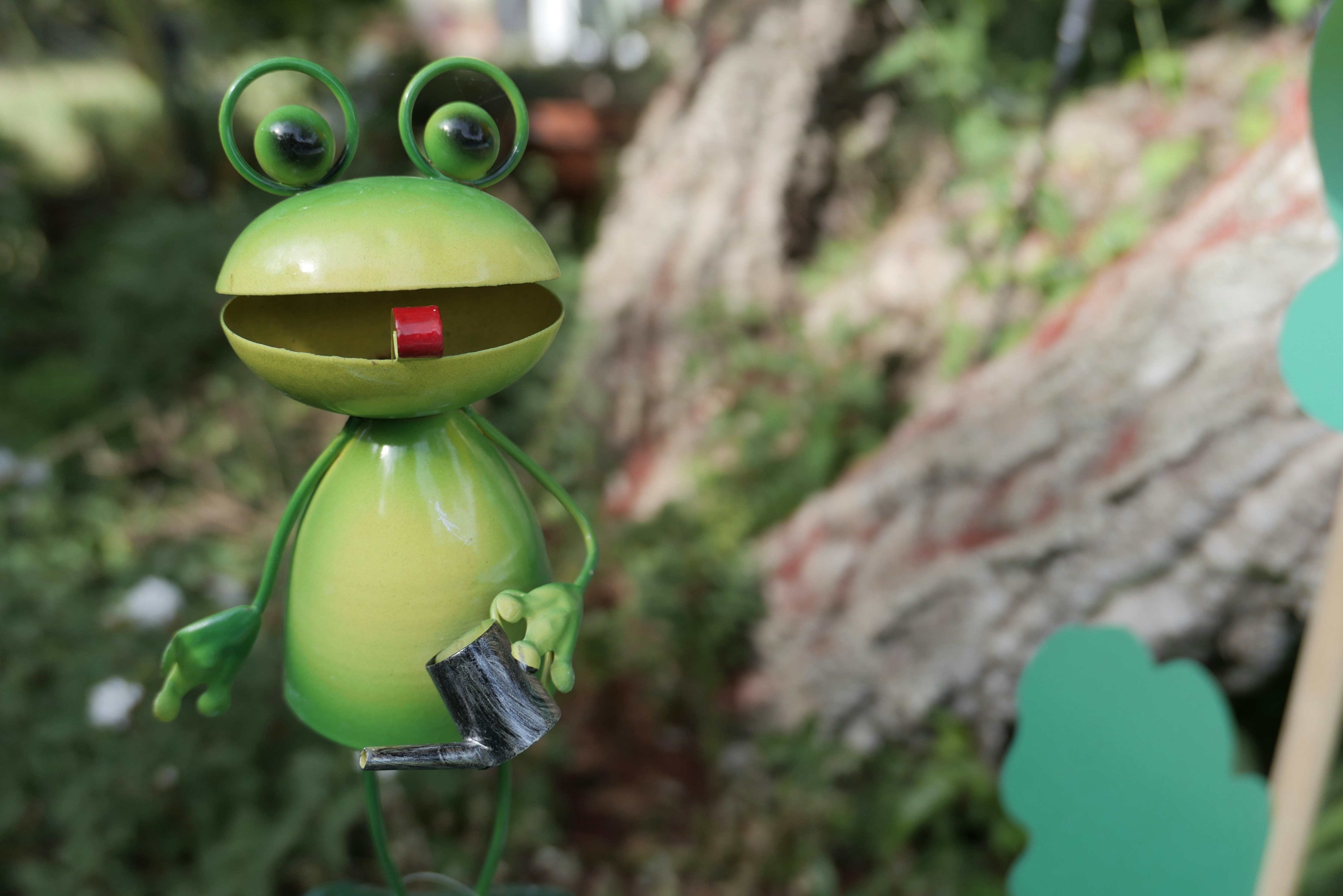 A whimsical frog statue smiling in a garden.
