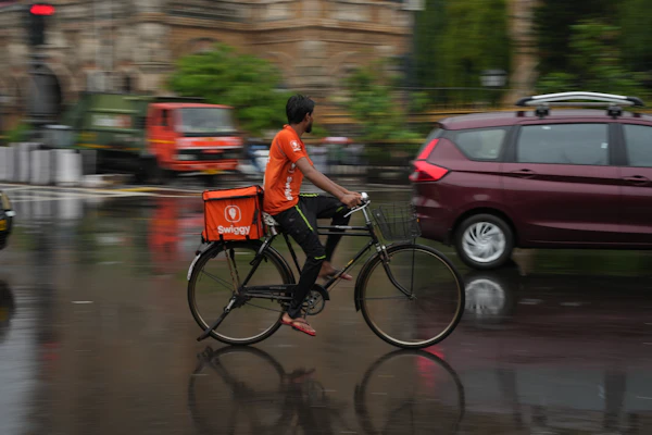 A delivery rider cycling through wet streets