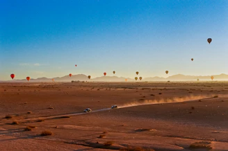 Hot air balloons float above the desert landscape