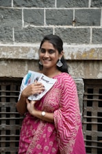 Smiling woman holds a booklet, looking at the camera.