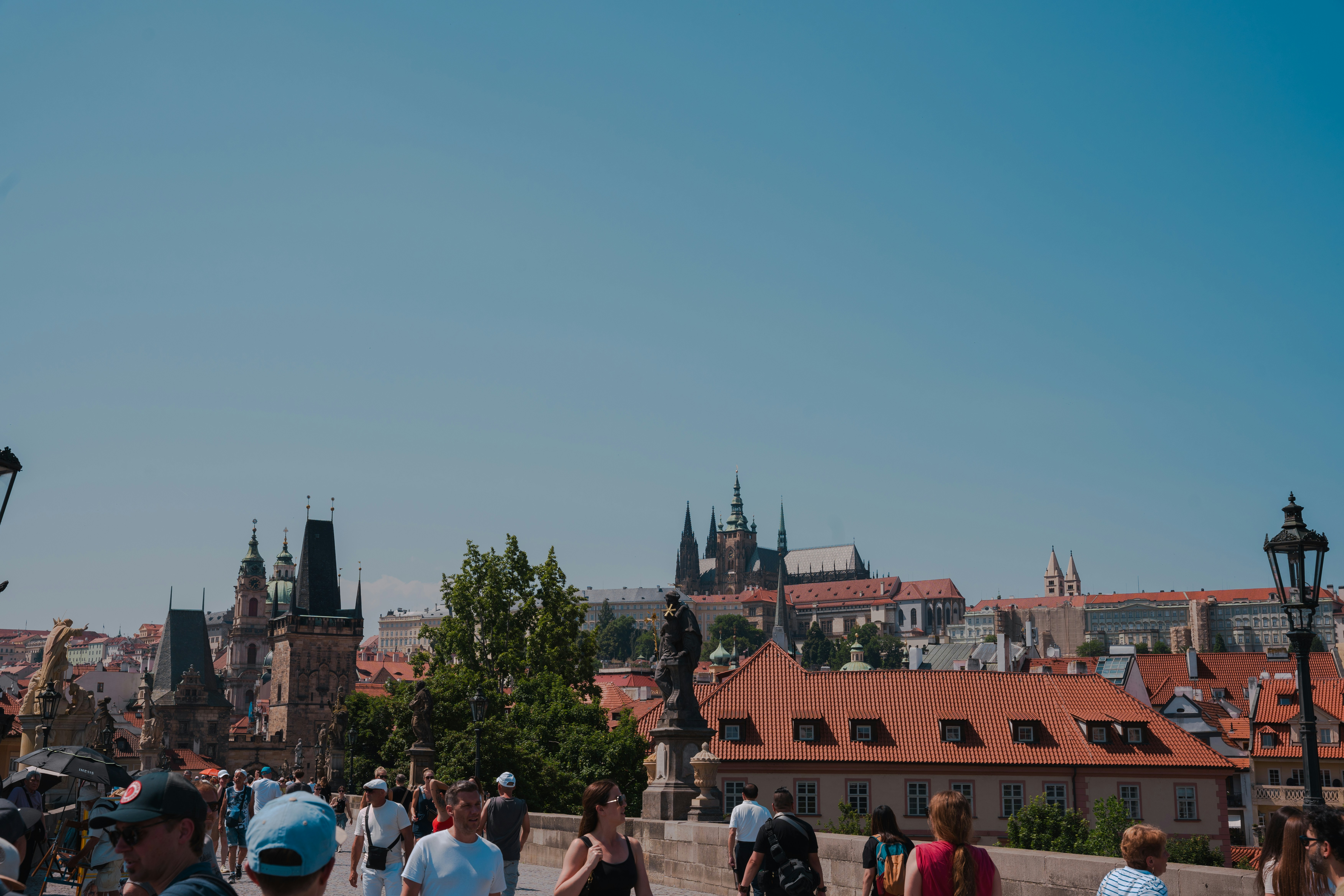 Crowds walk on a bridge towards a city skyline.
