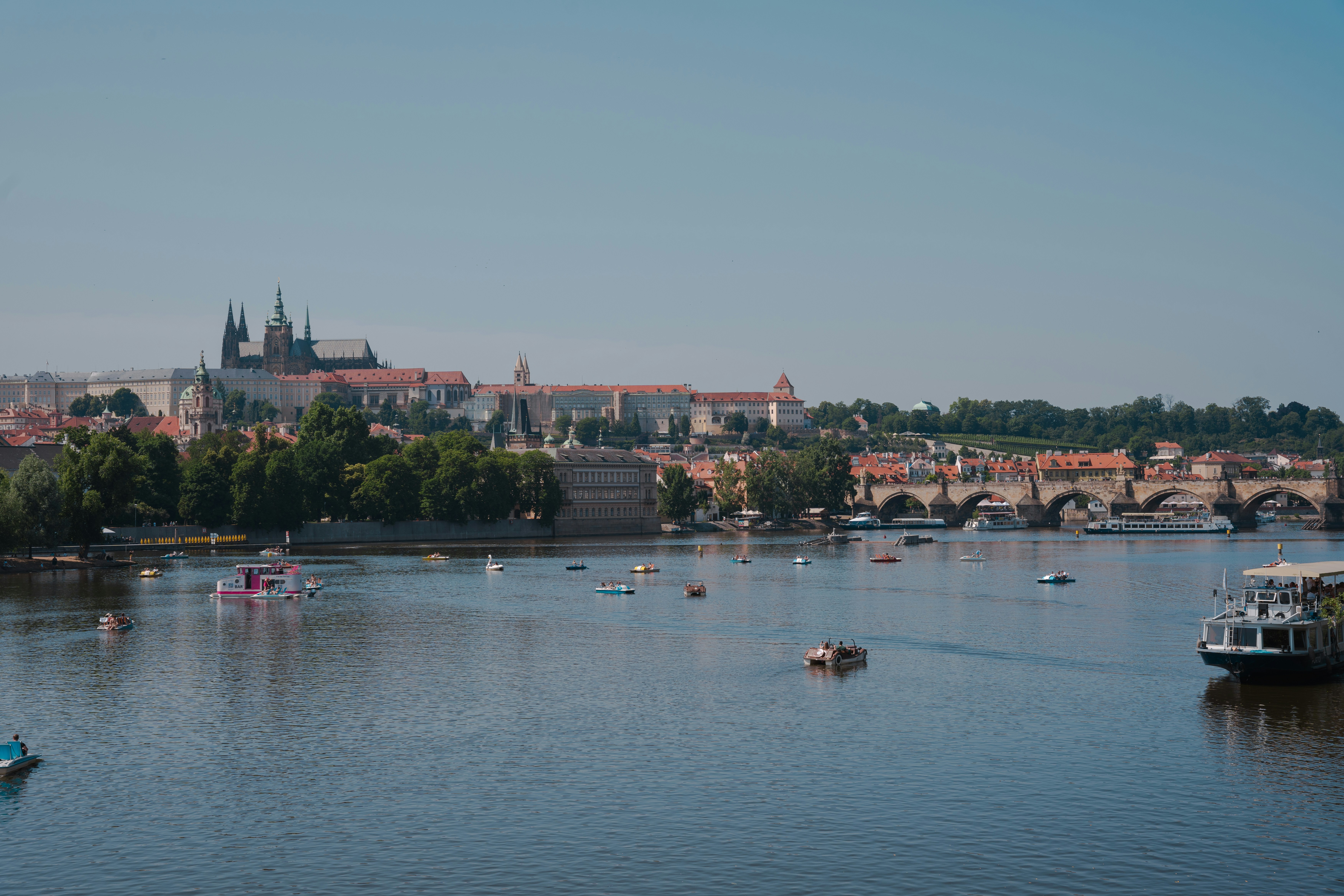 Prague castle overlooks a river with boats.