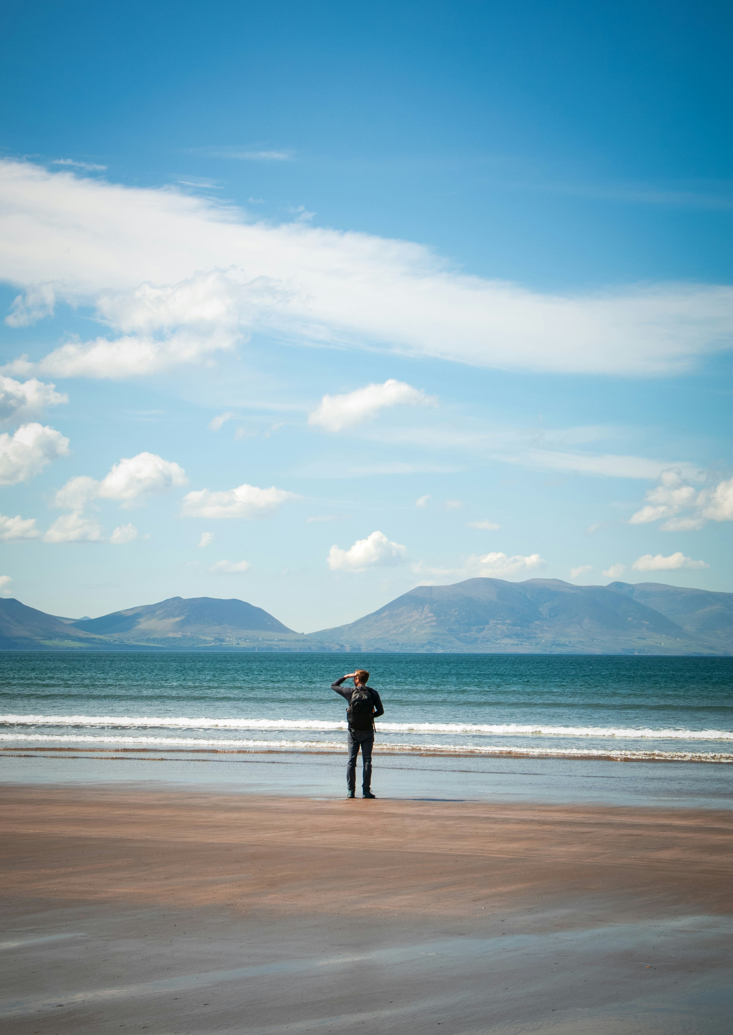 Uomo su una spiaggia che guarda l'oceano.