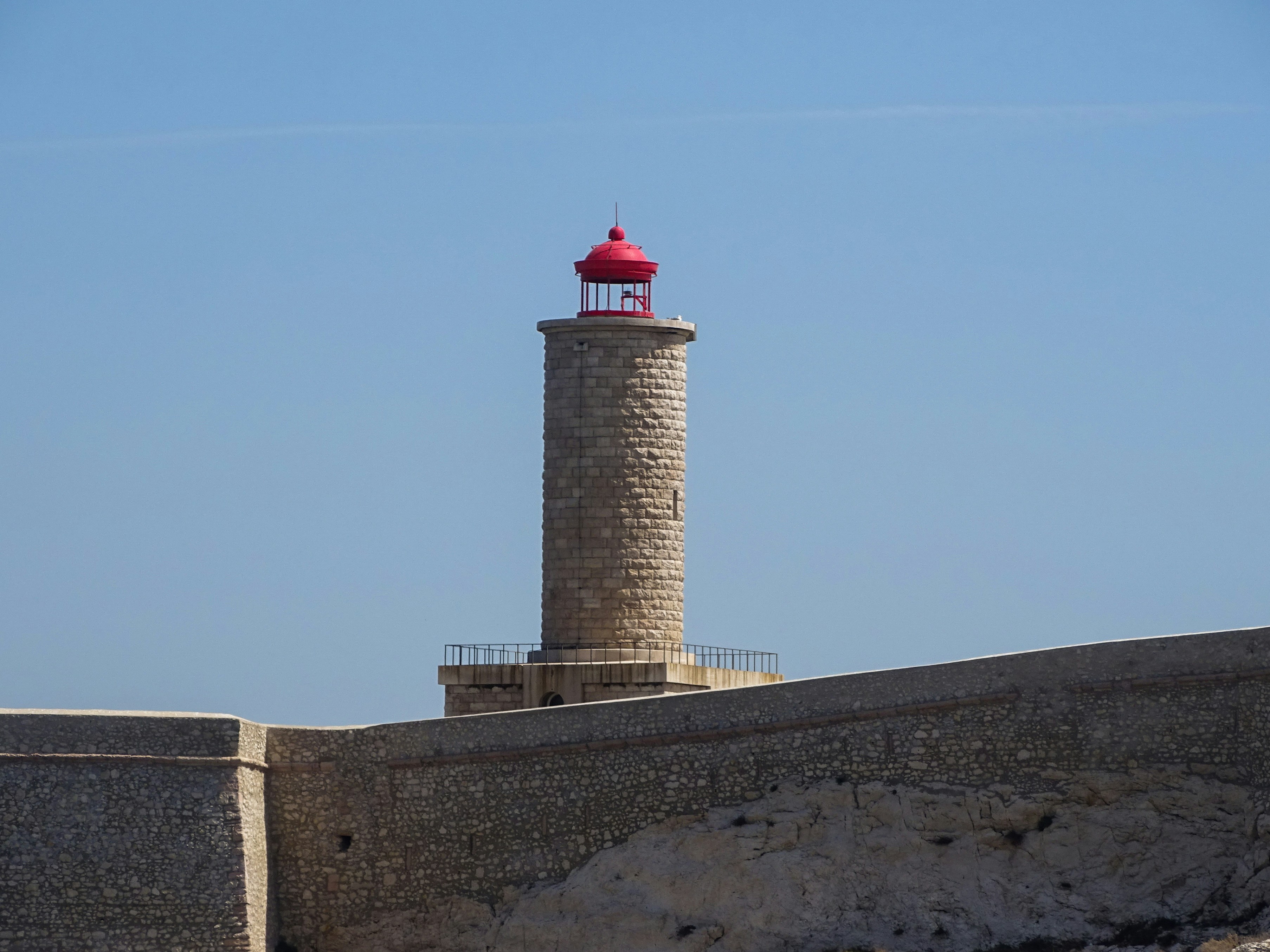 A lighthouse stands tall under a bright blue sky.