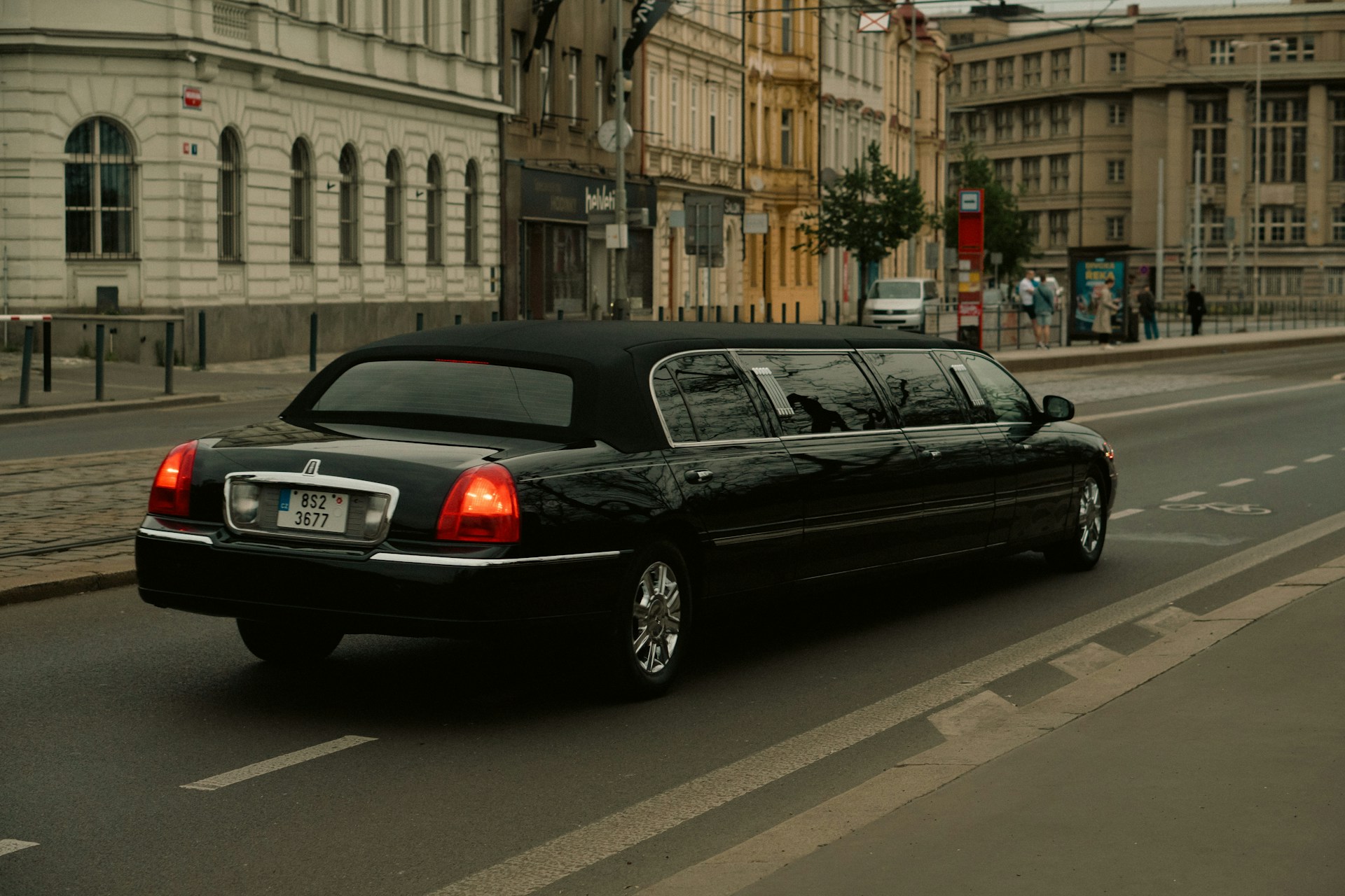 A black limousine travels down a city street.