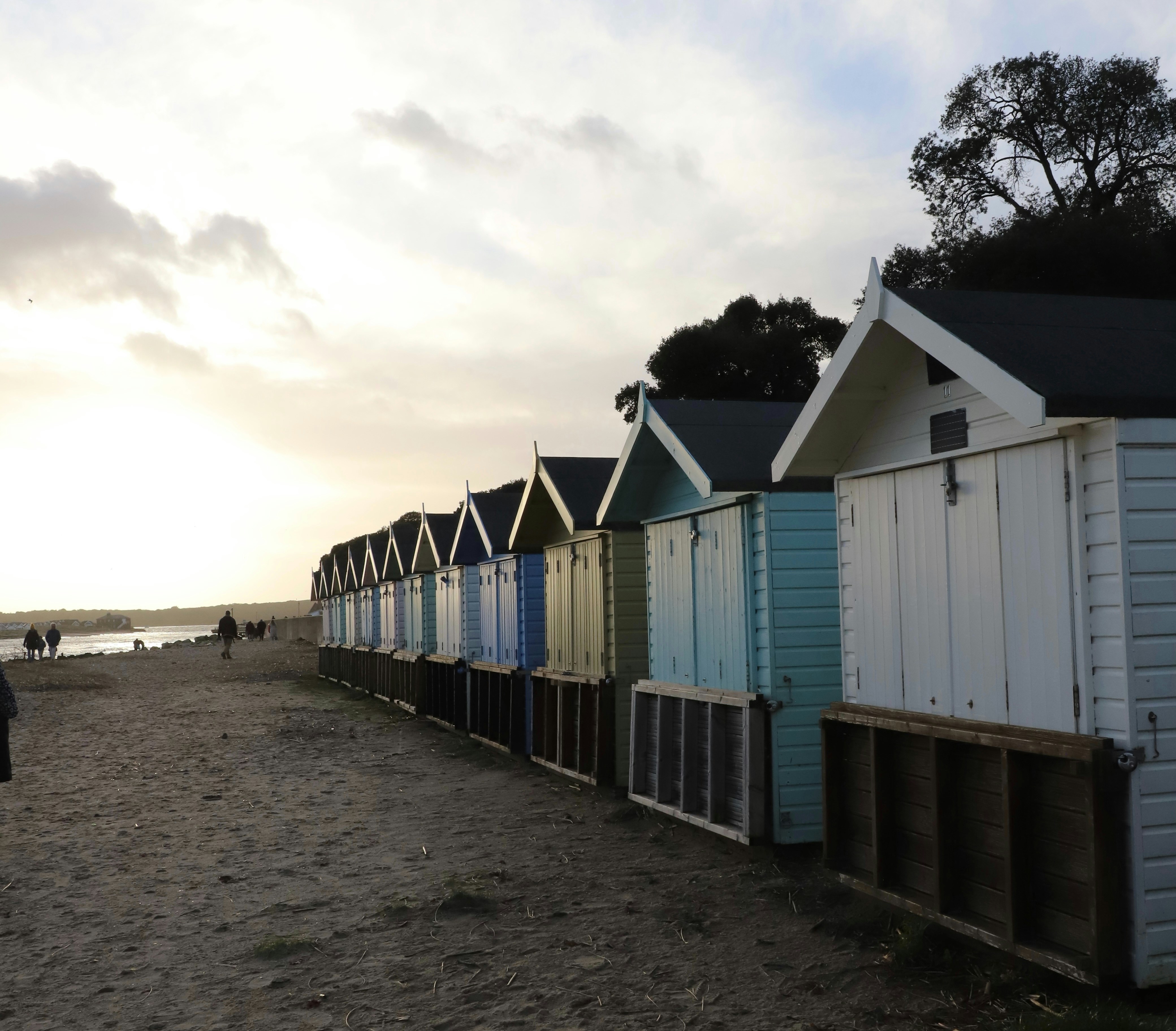 Colorful beach huts line a sandy shore