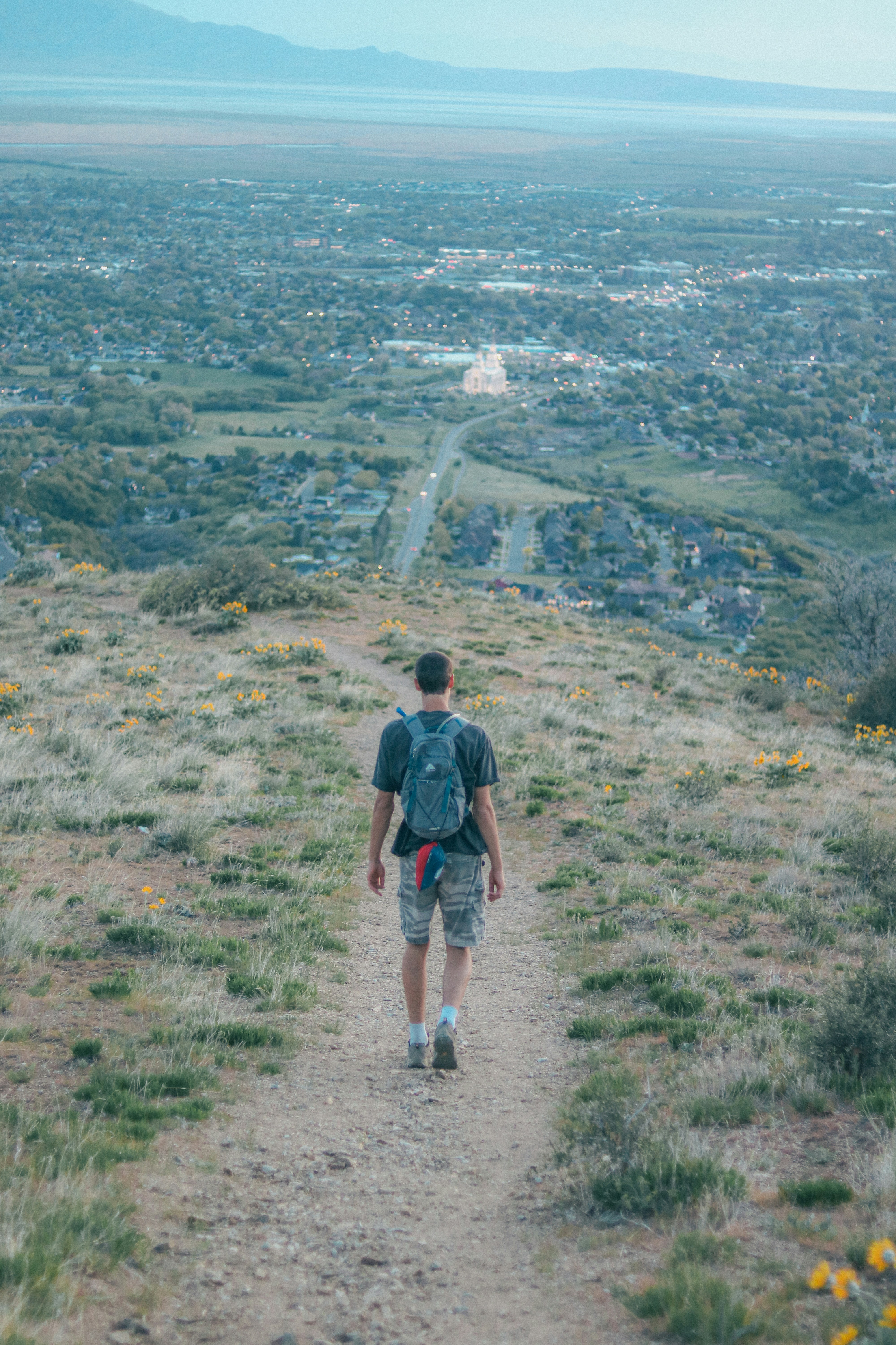 Randonneur descendant un sentier surplombant une ville.