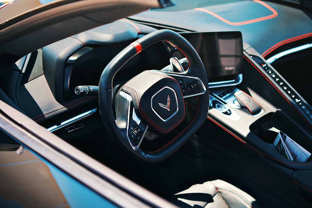 A modern car interior showcasing the steering wheel., Black Chevrolet Corvette C8 Stringray car photography at Charlotte car show.