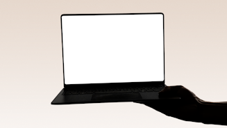 A hand holds a laptop with a blank screen.