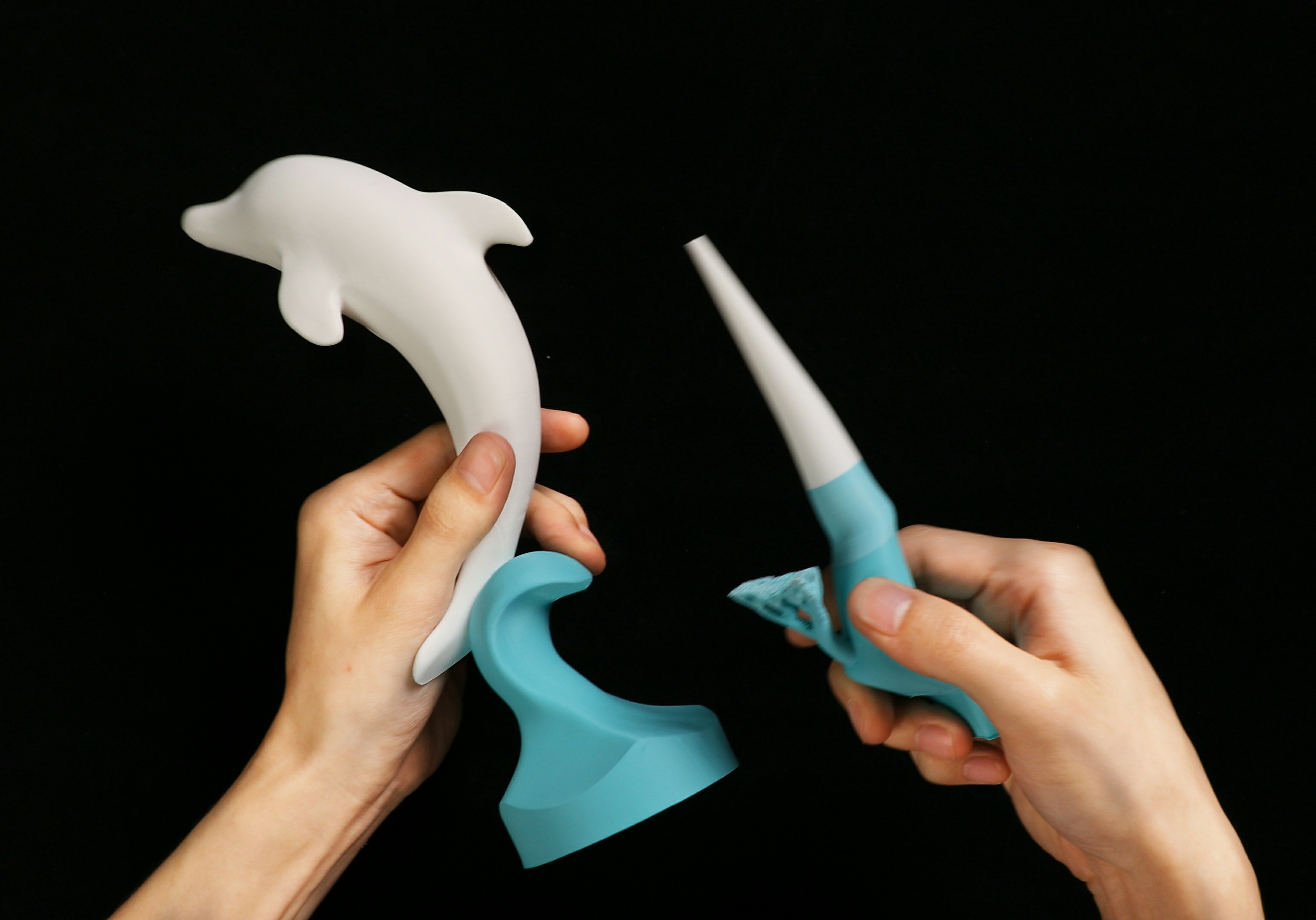 Hands hold a dolphin sculpture and its stylus.