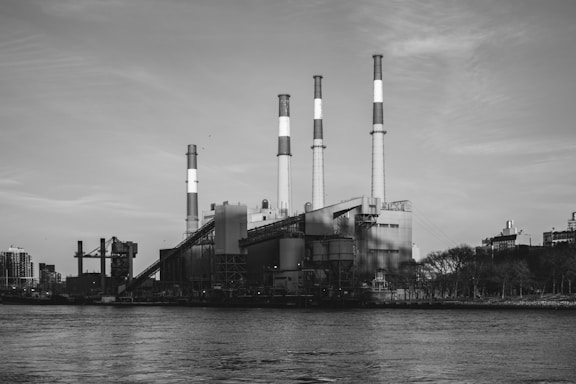 Factory with smoke stacks along a waterfront.
