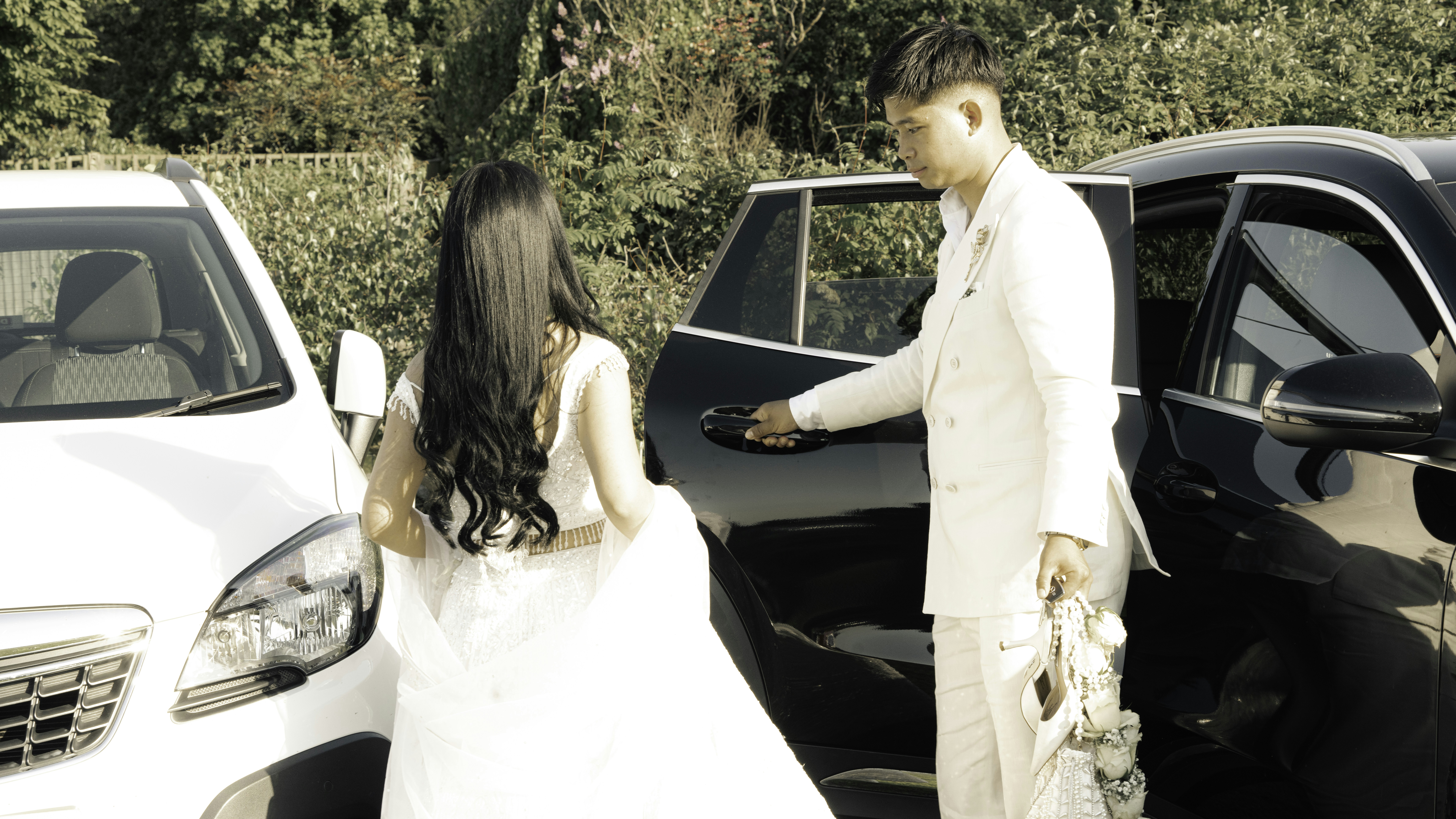A groom opens a car door for his bride.
