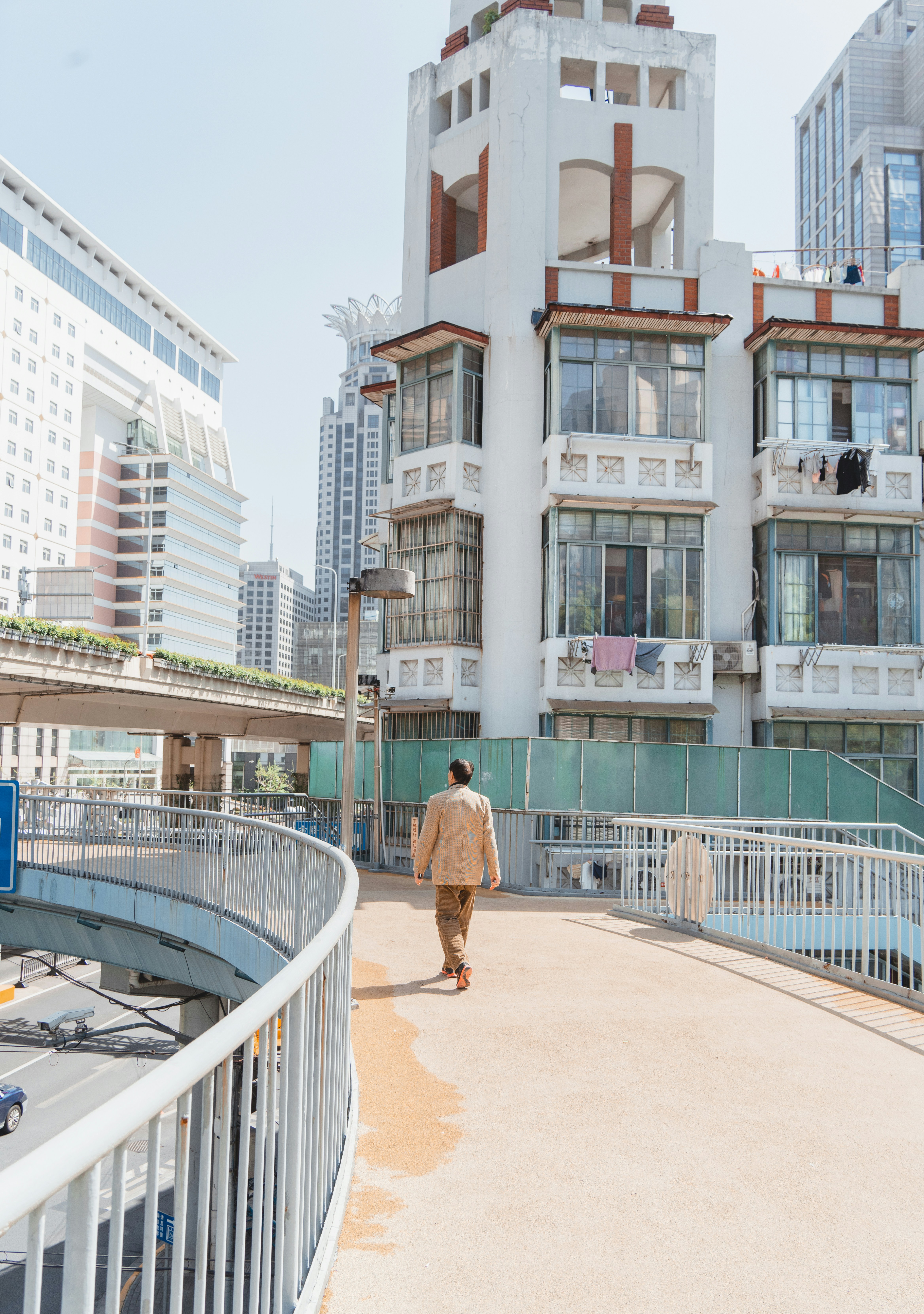 A person walks on a bridge near buildings