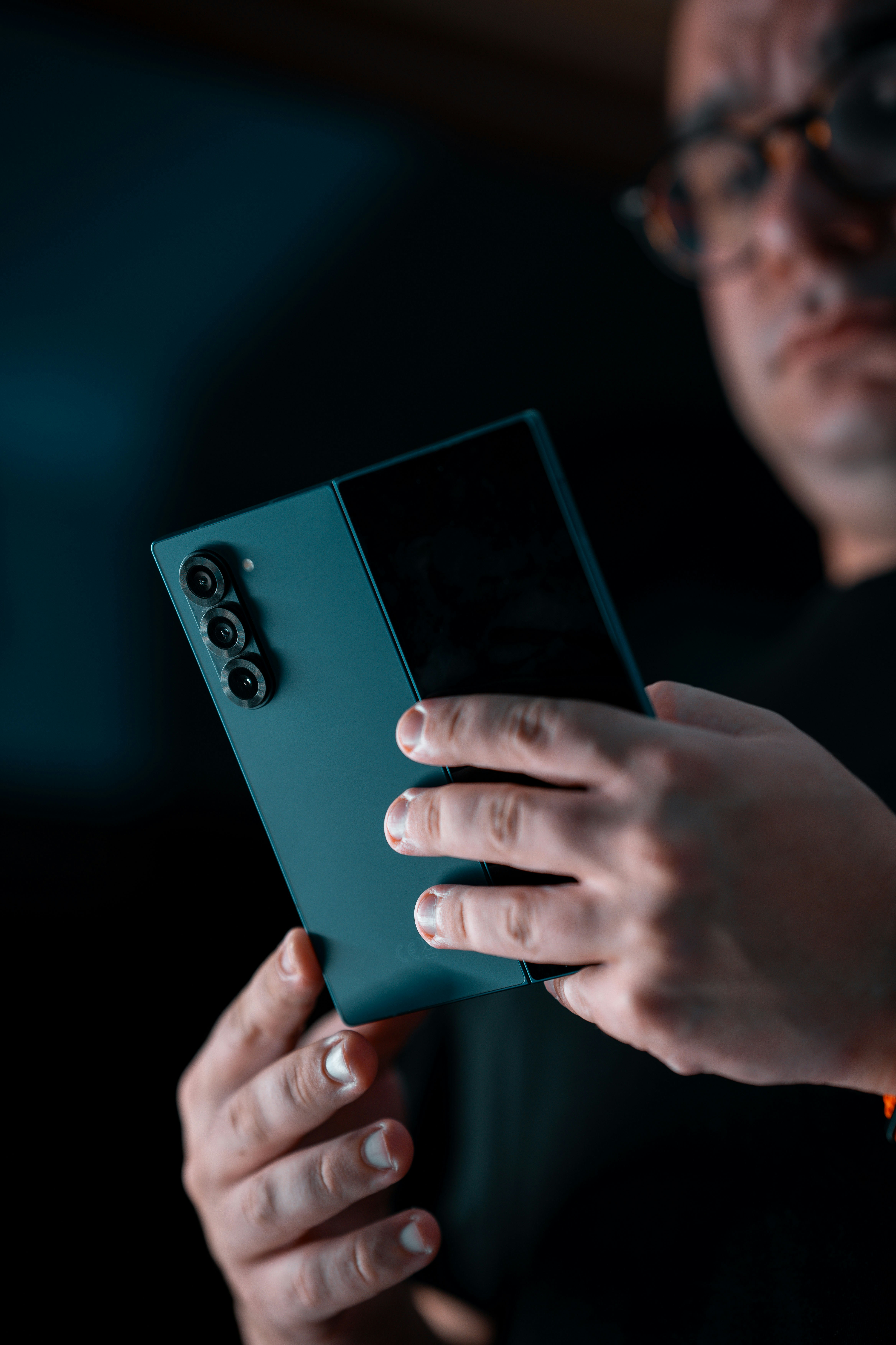 Hombre sosteniendo un teléfono inteligente plegado con una cámara.