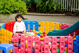 A little girl plays in a colorful ball pit.