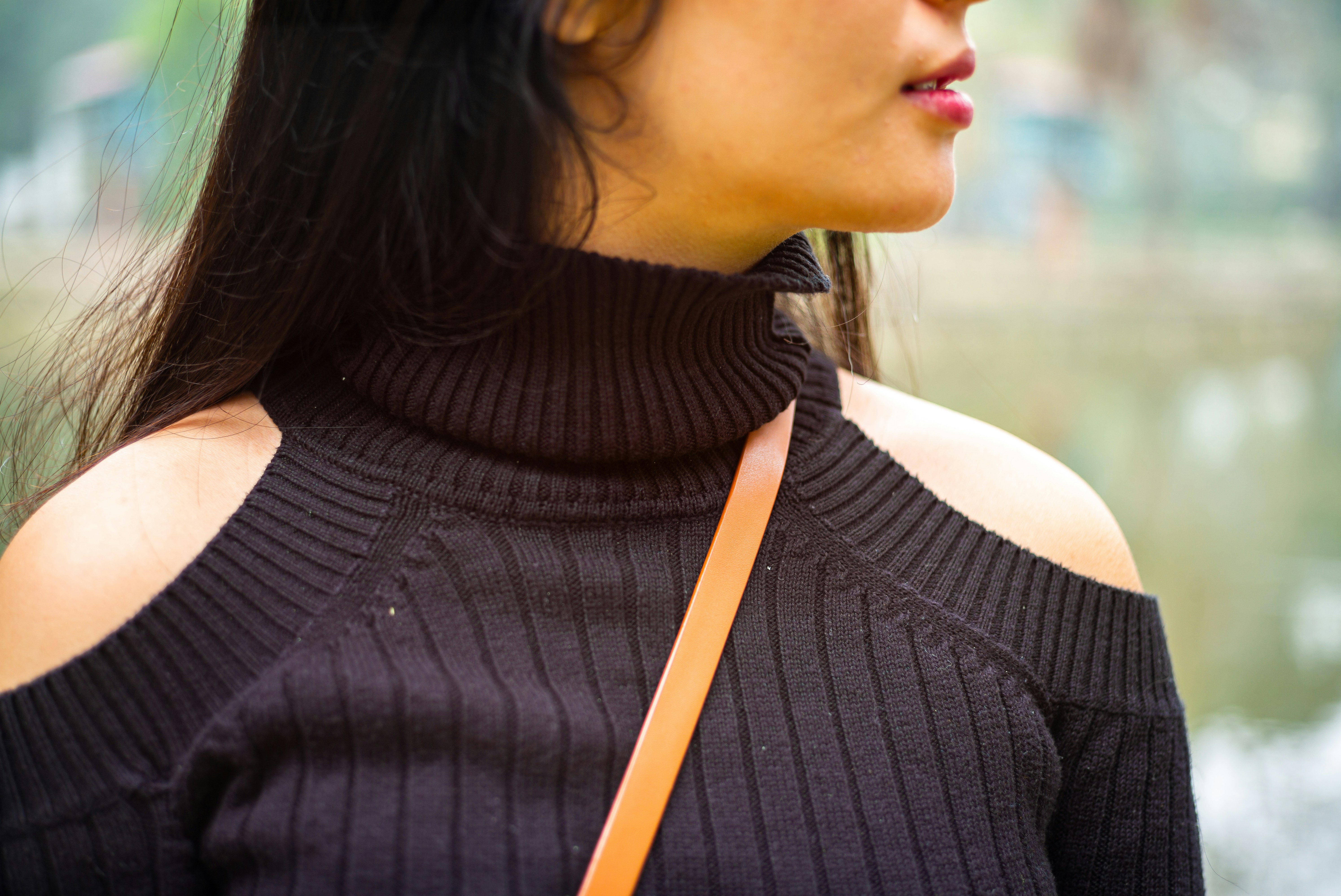 3 Unexpected Ways to Wear a Turtleneck That Aren’t Basic or Bulky – A woman in a black shoulder-cut sweater.
