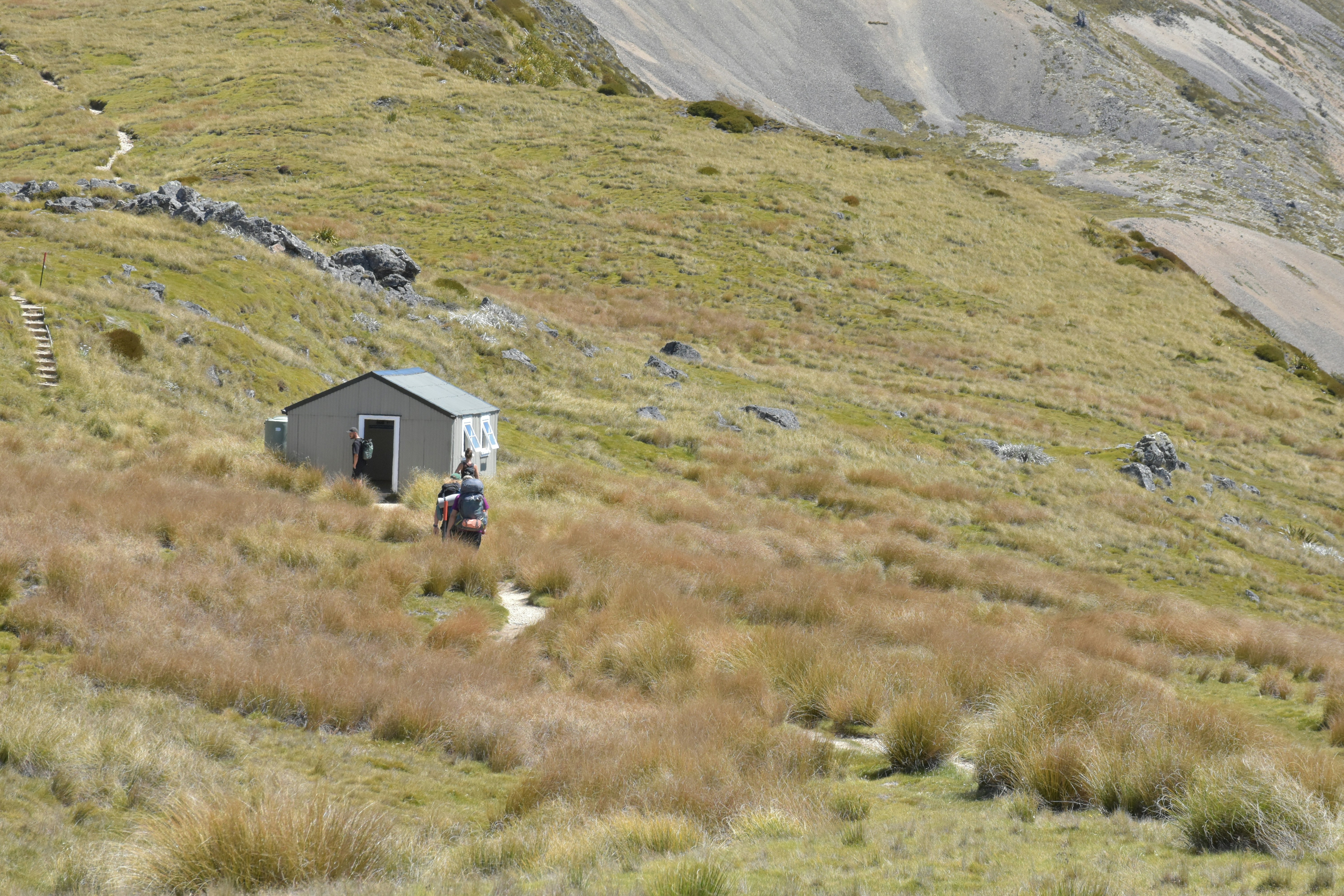 A small building sits on a grassy hillside.