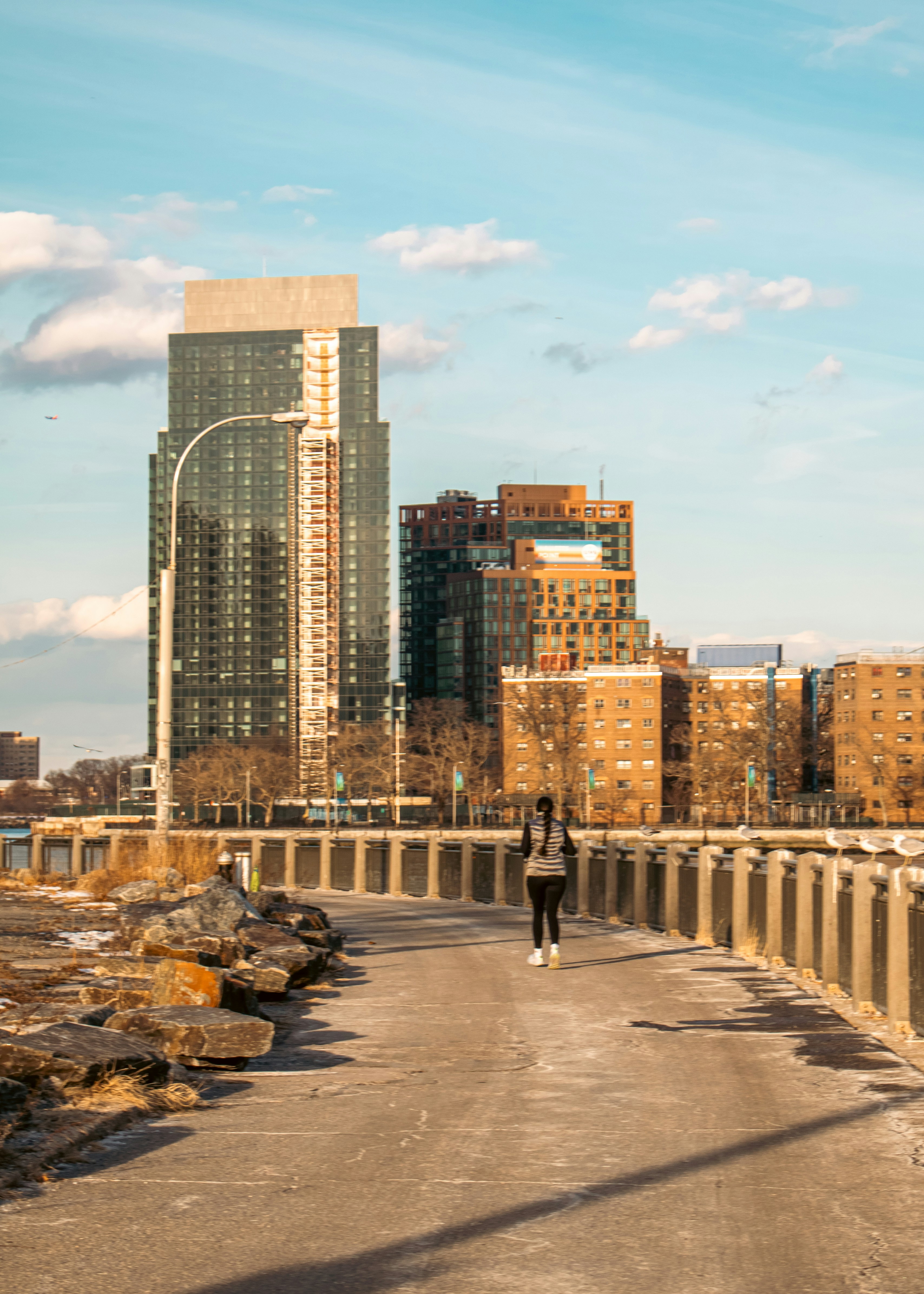 A person walks near city buildings on a sunny day.