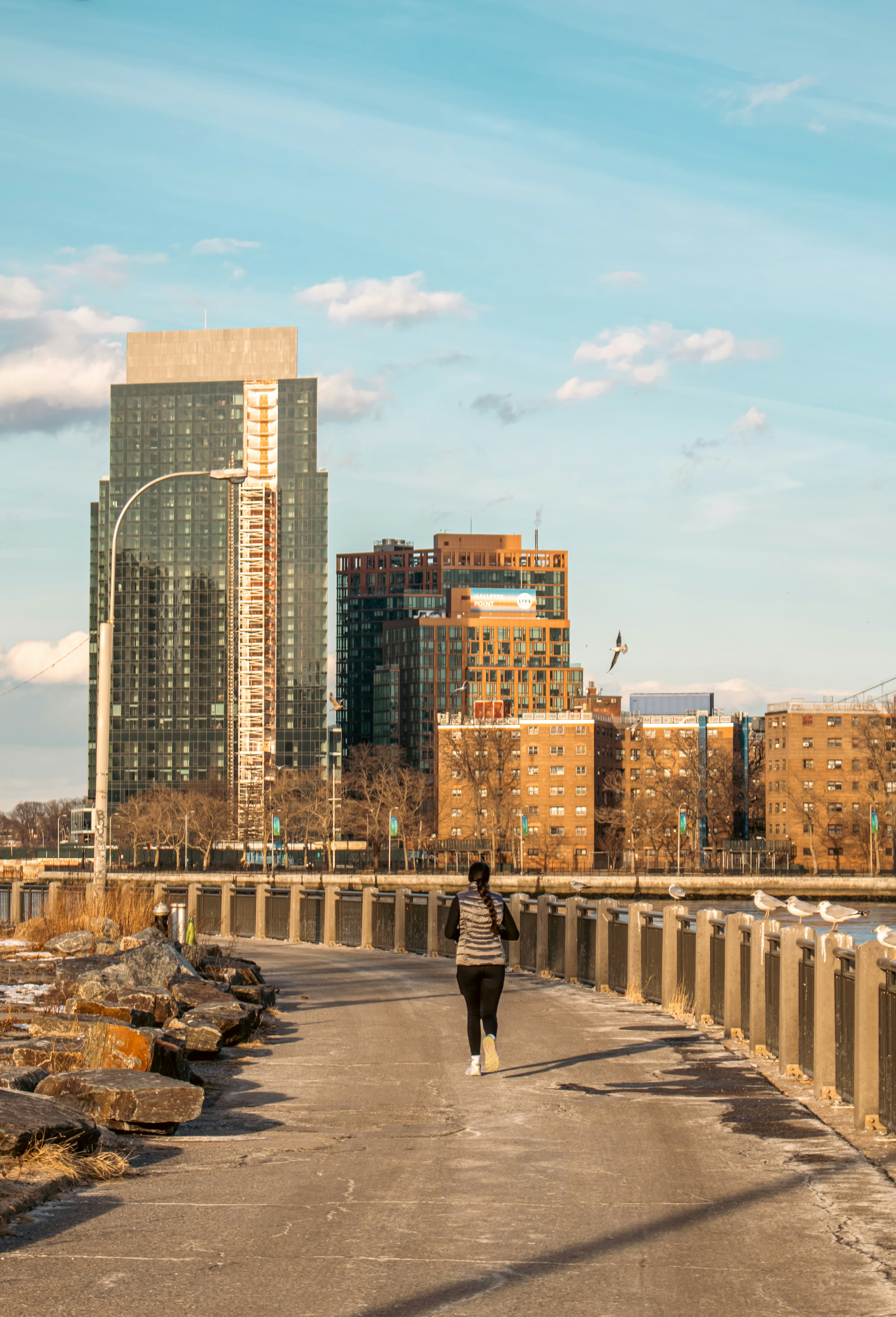 A person runs on a path by city buildings.